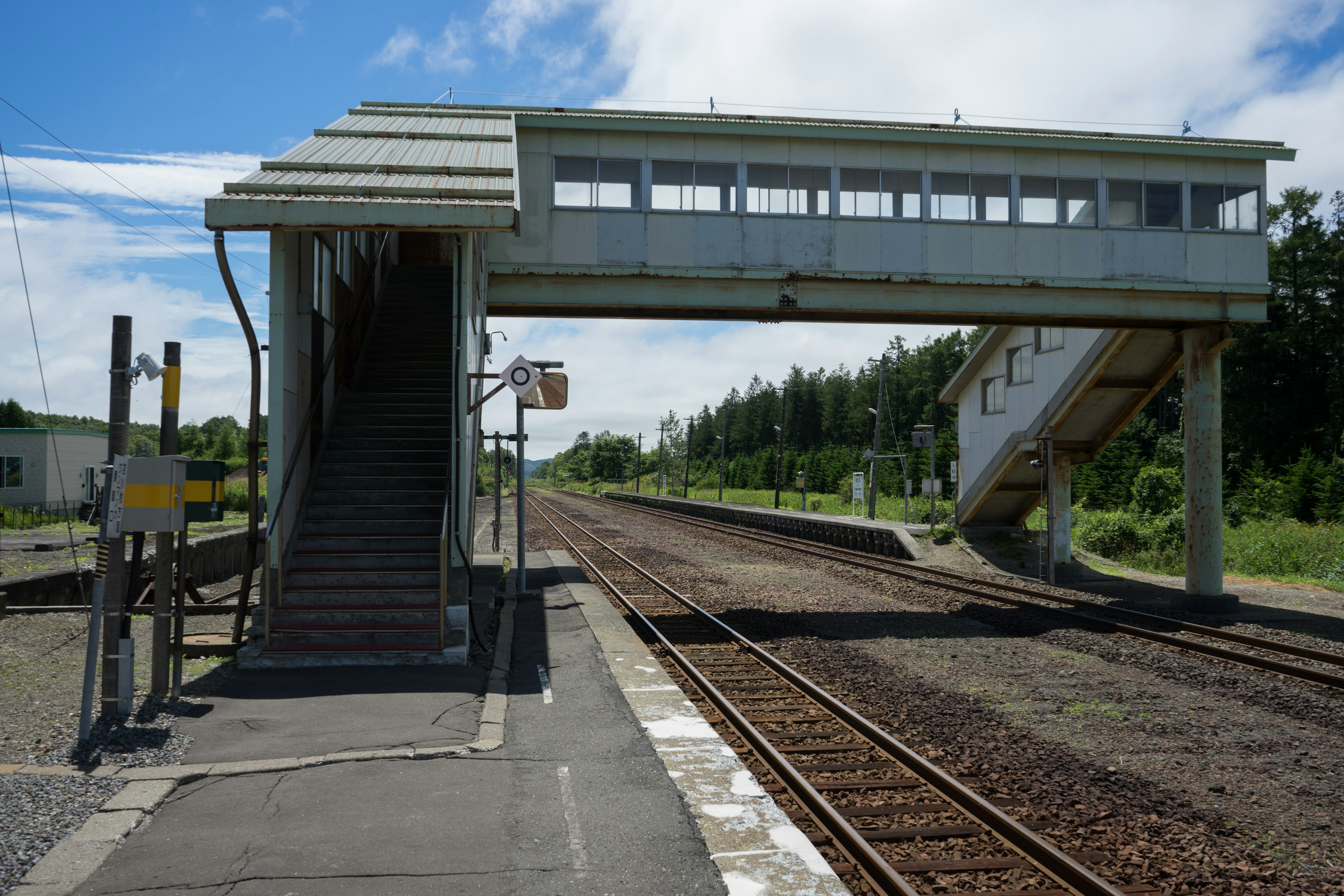 Blick auf eine erhöhte Fußgängerbrücke an einem Bahnhof mit Gleisen