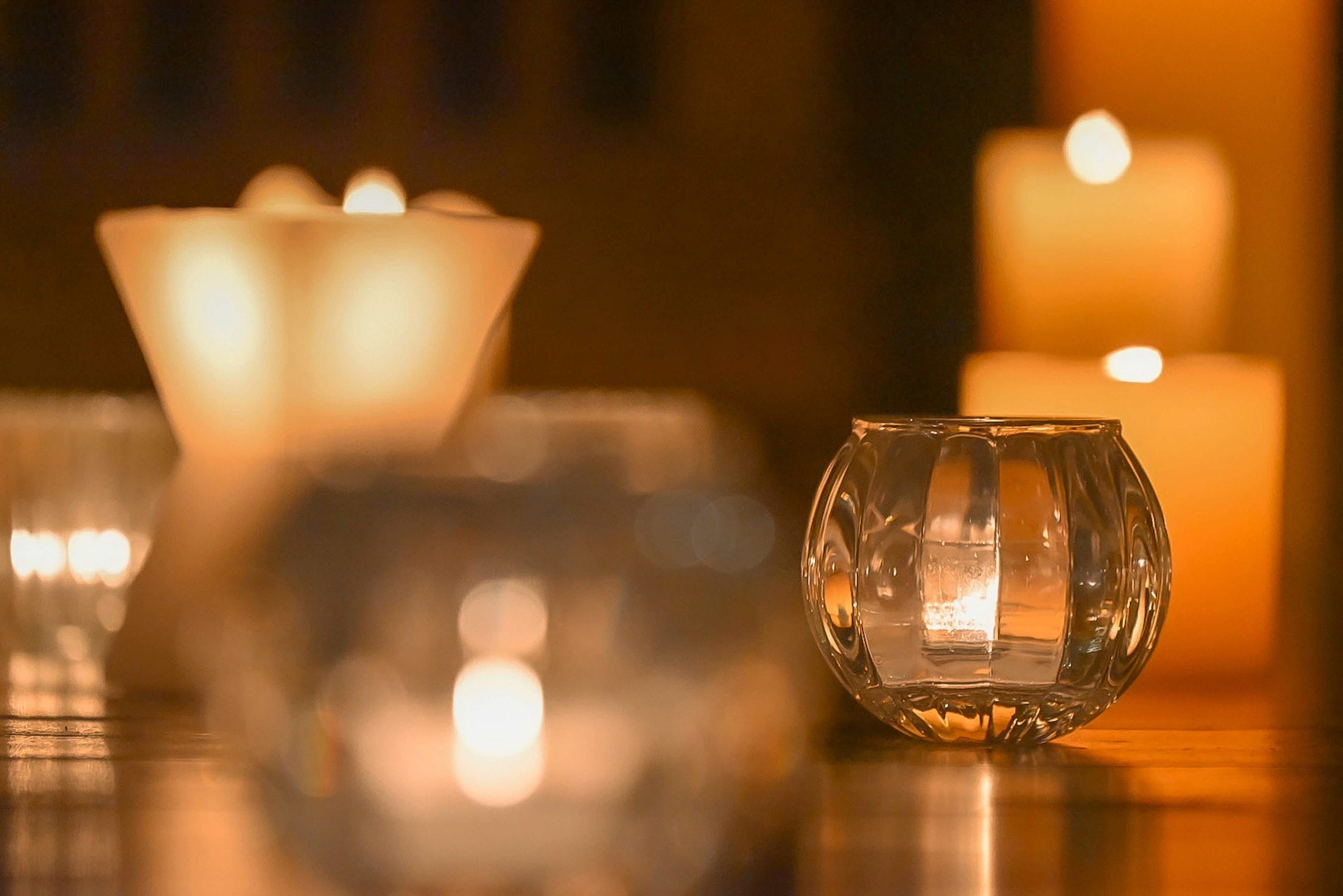 Ambiance chaleureuse avec des bougies et des porte-bougies en verre disposés de manière artistique