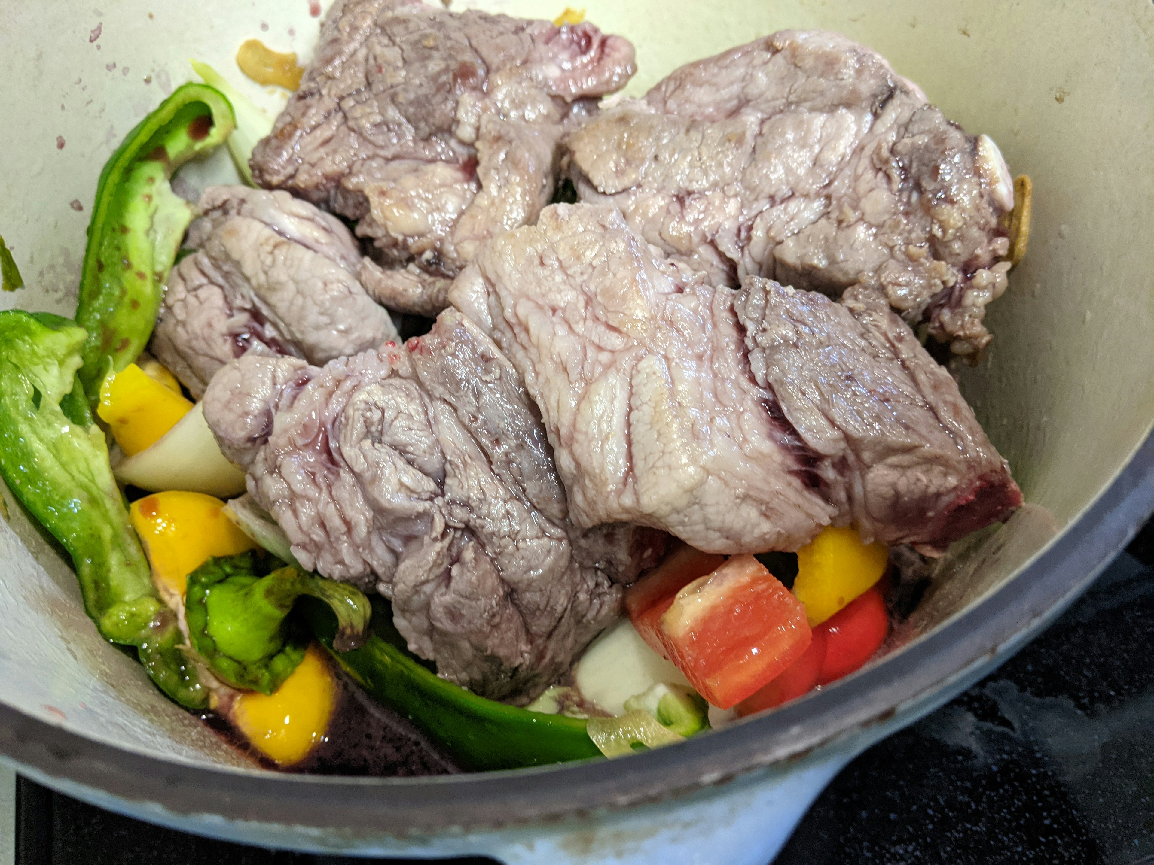 Trozos de carne en una olla con verduras coloridas