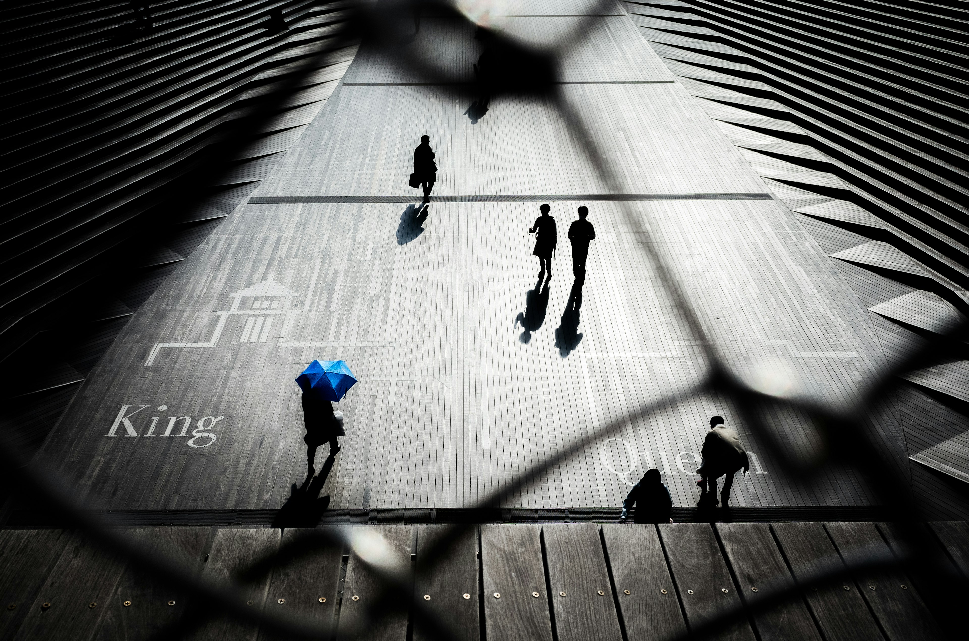 Persone che camminano su gradini con un ombrello blu in evidenza e la parola King