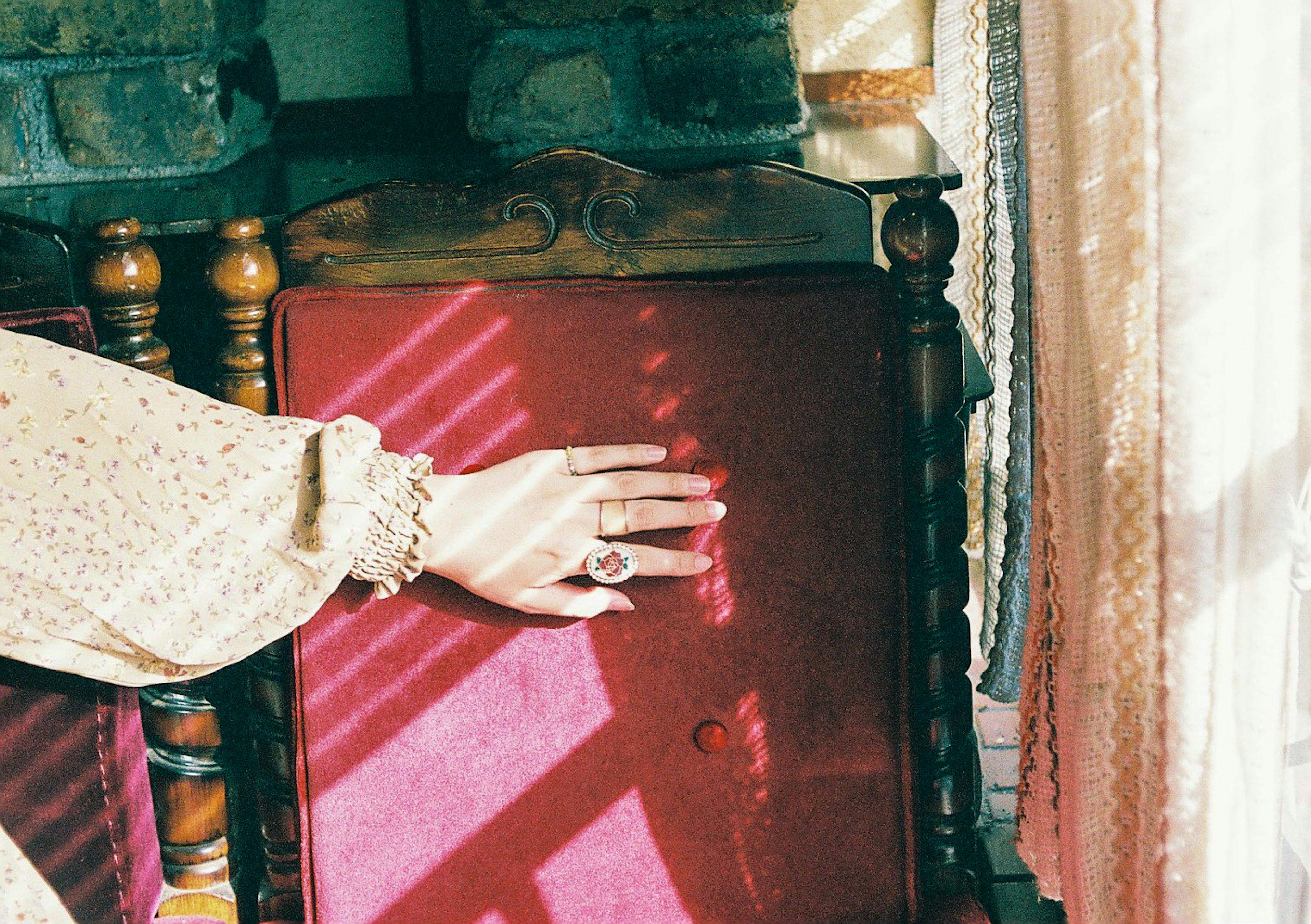 Close-up of a woman's hand resting on a red chair with a ring