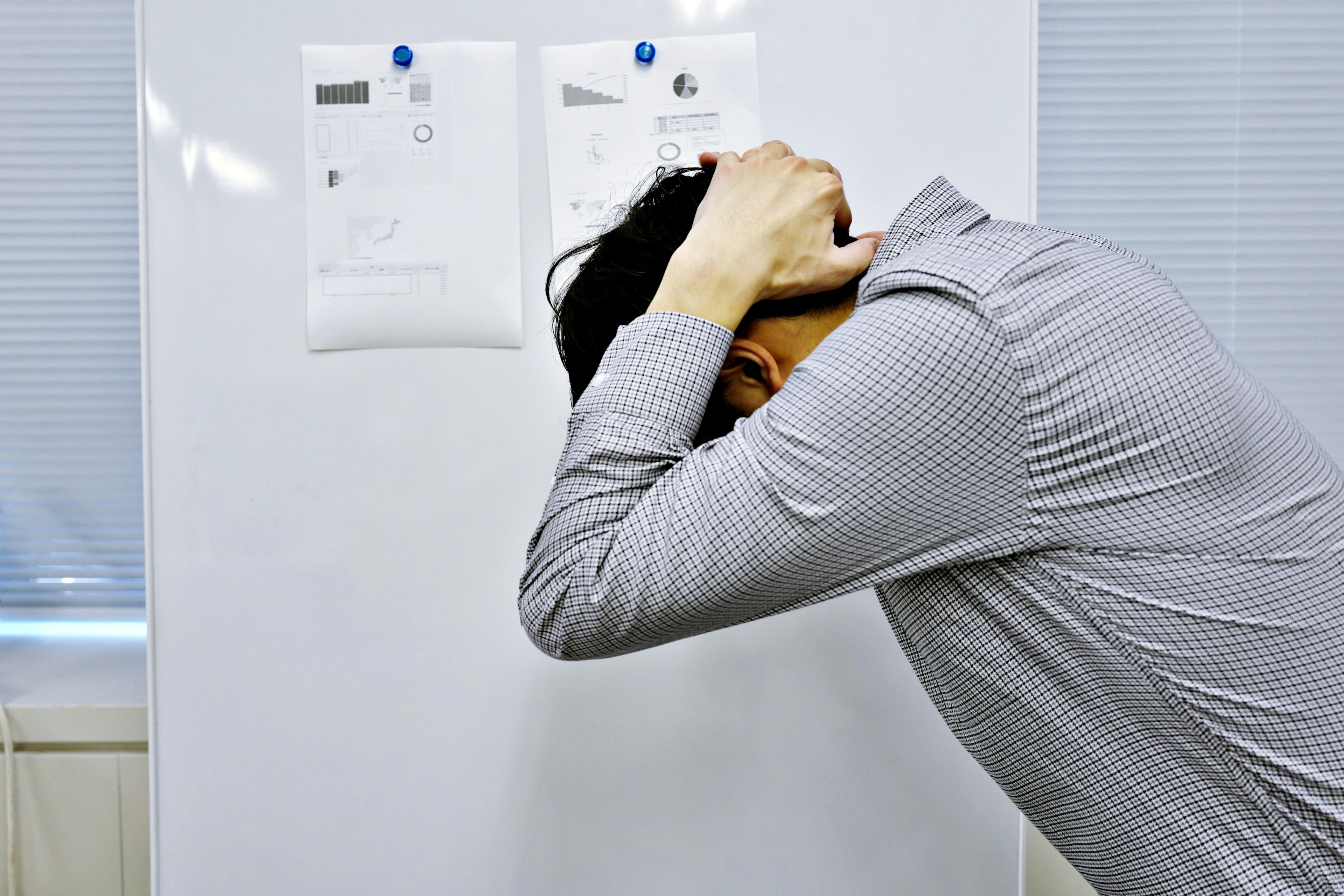 Stressed man holding his head in front of a white board