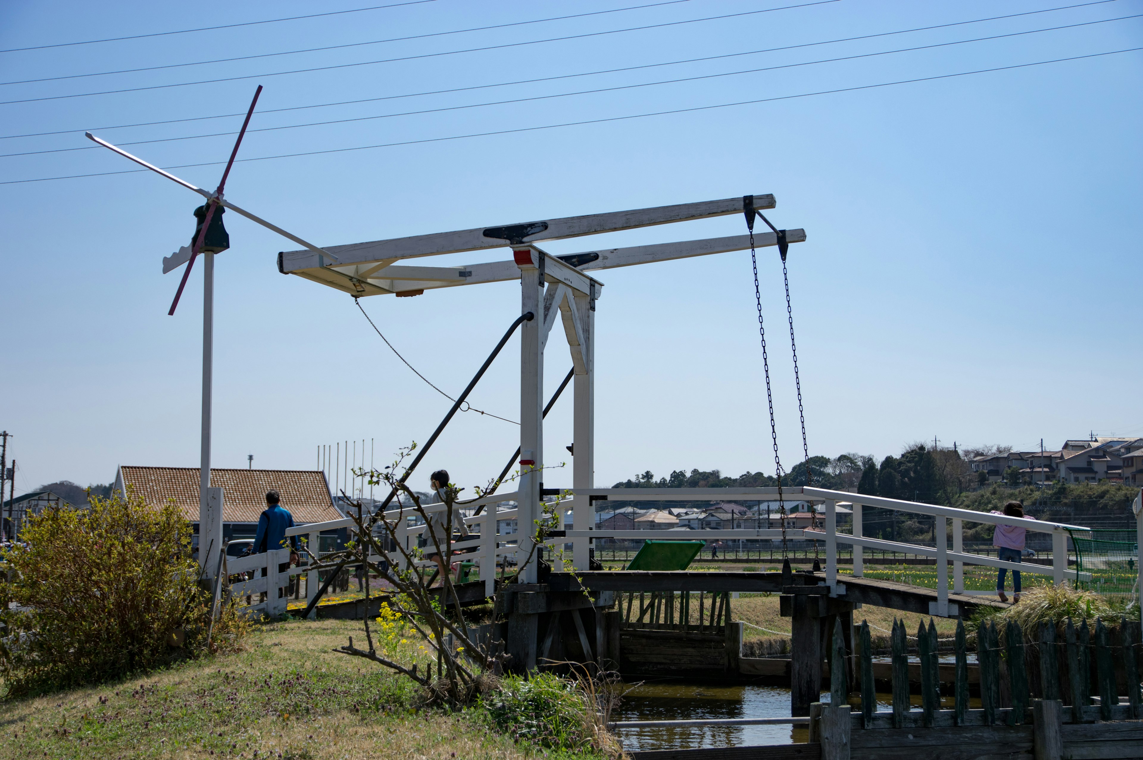 Scenic view of a white bridge and water wheel under a blue sky