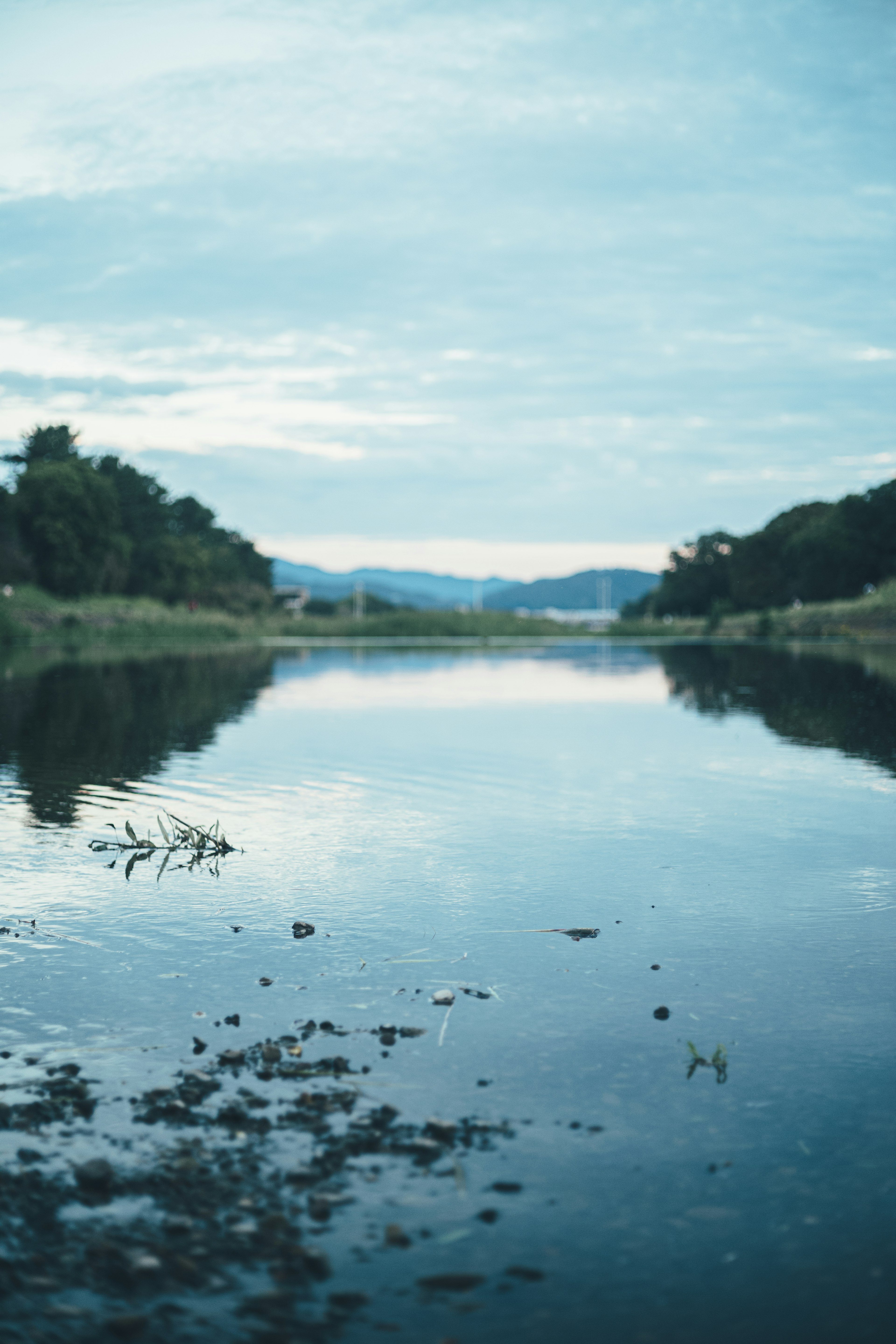 Serene river reflecting a cloudy blue sky