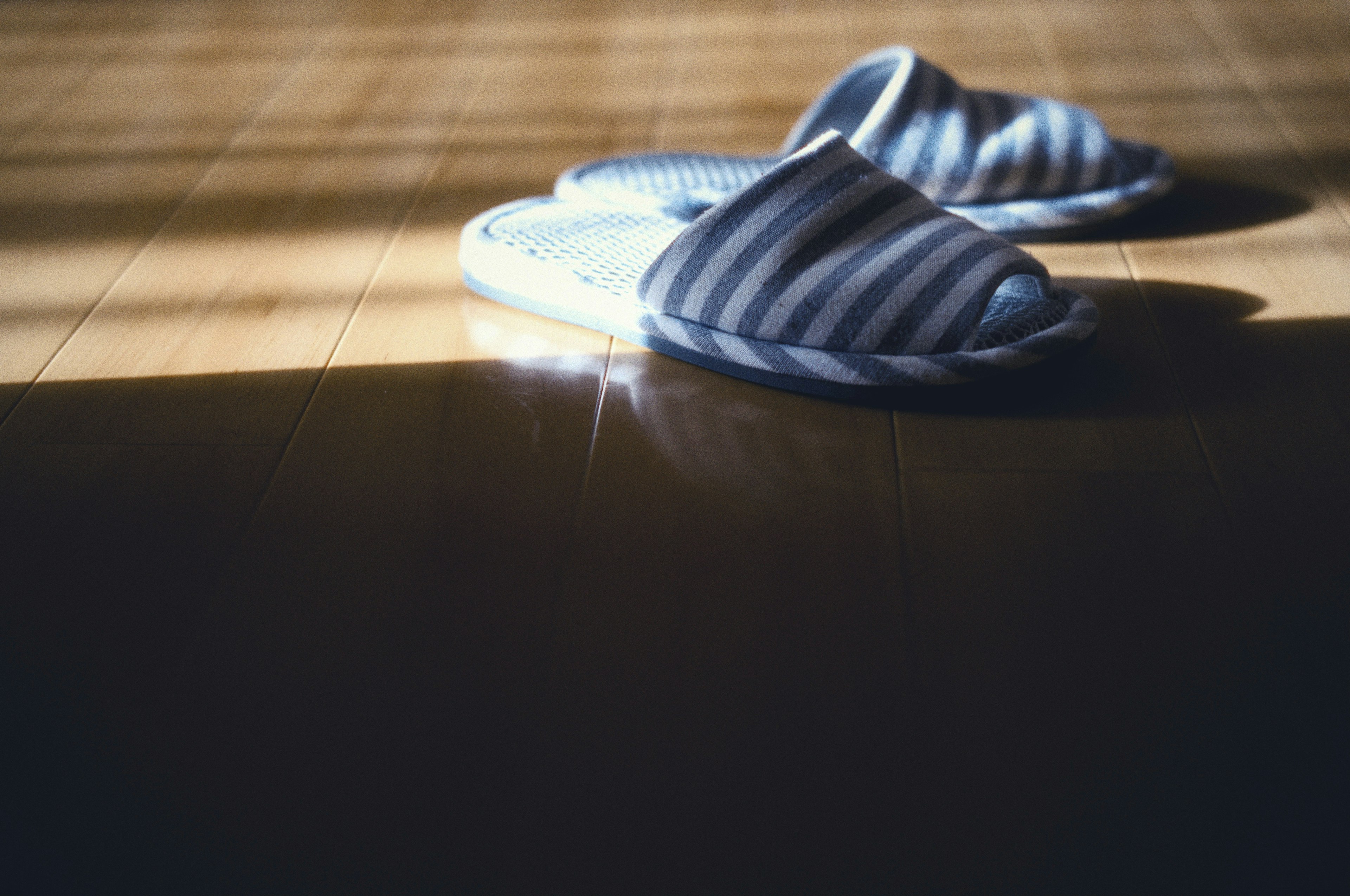 Blue striped slippers resting on a wooden floor in soft light