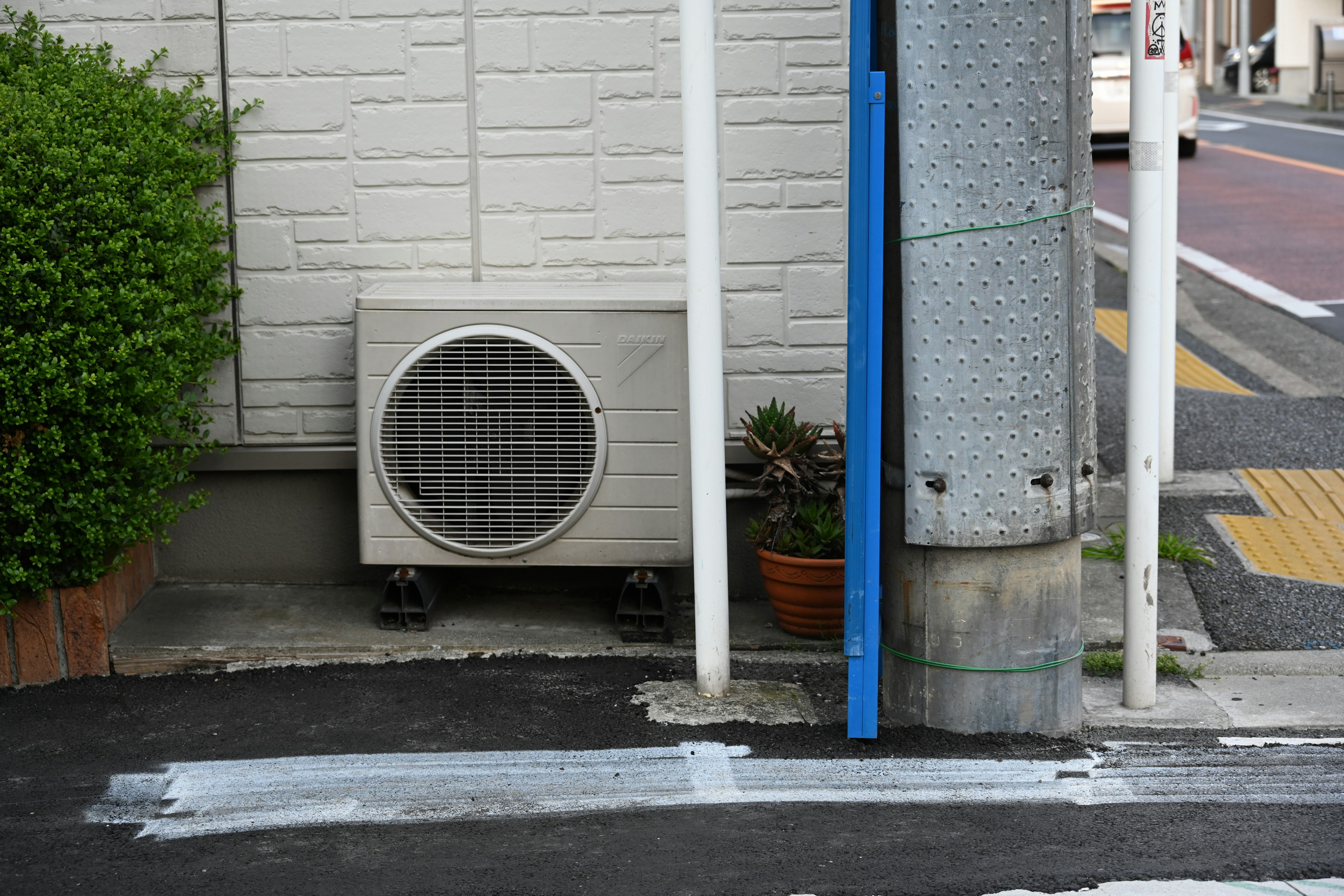 Air conditioning unit located at a street corner with surrounding plants