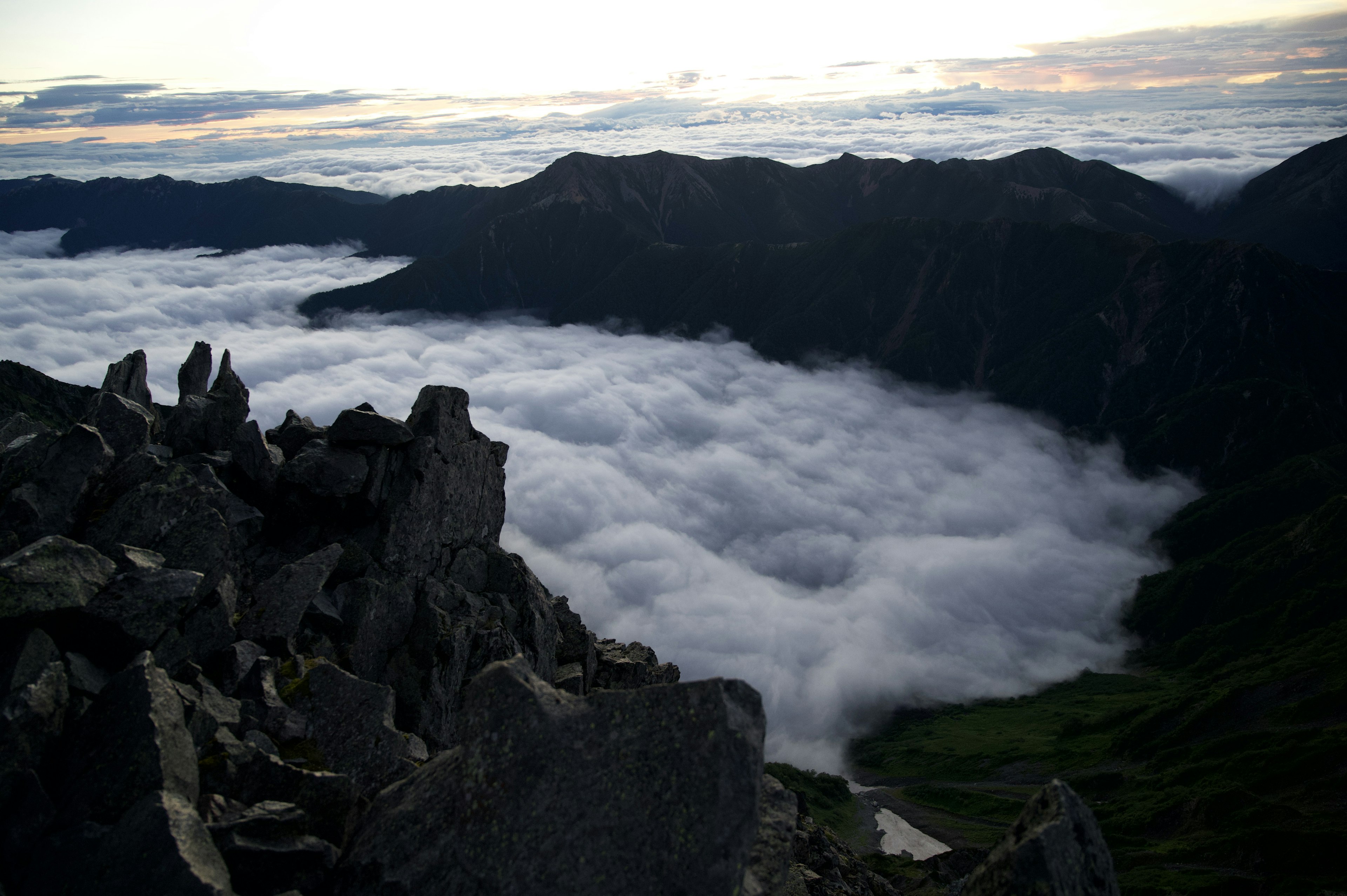 Vista de un mar de nubes desde la cima de una montaña durante el atardecer