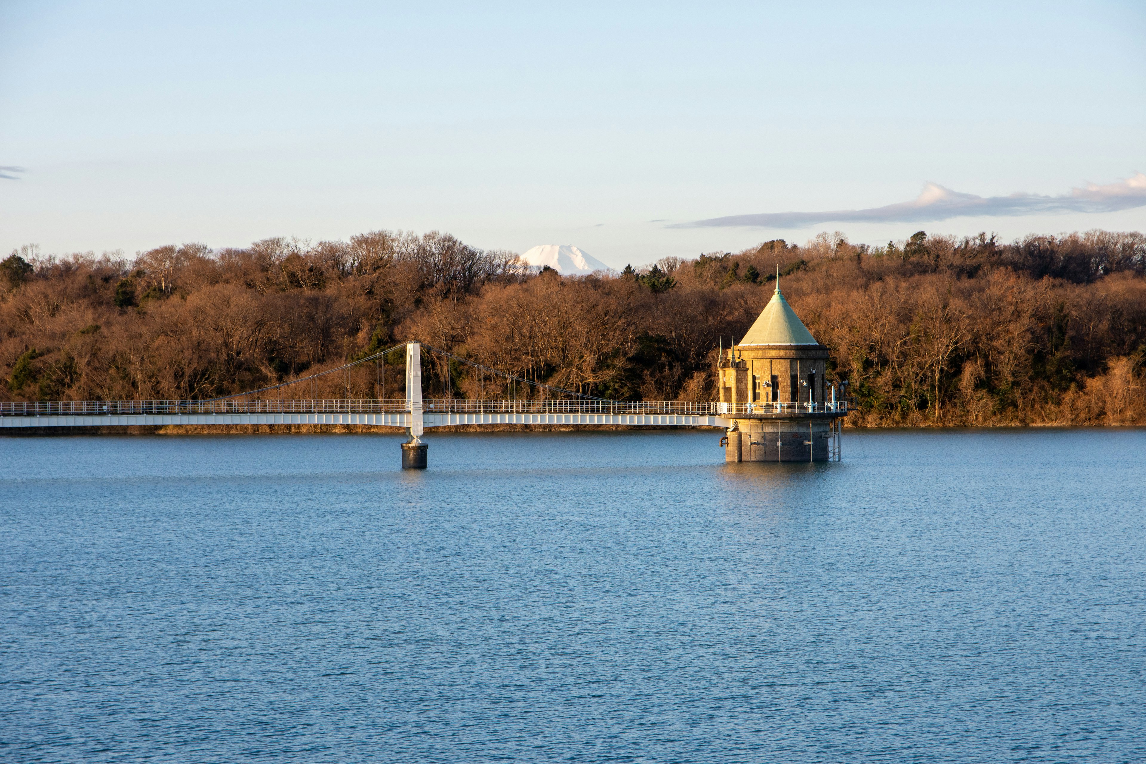 Vista escénica de una pequeña torre en un lago con un puente colgante