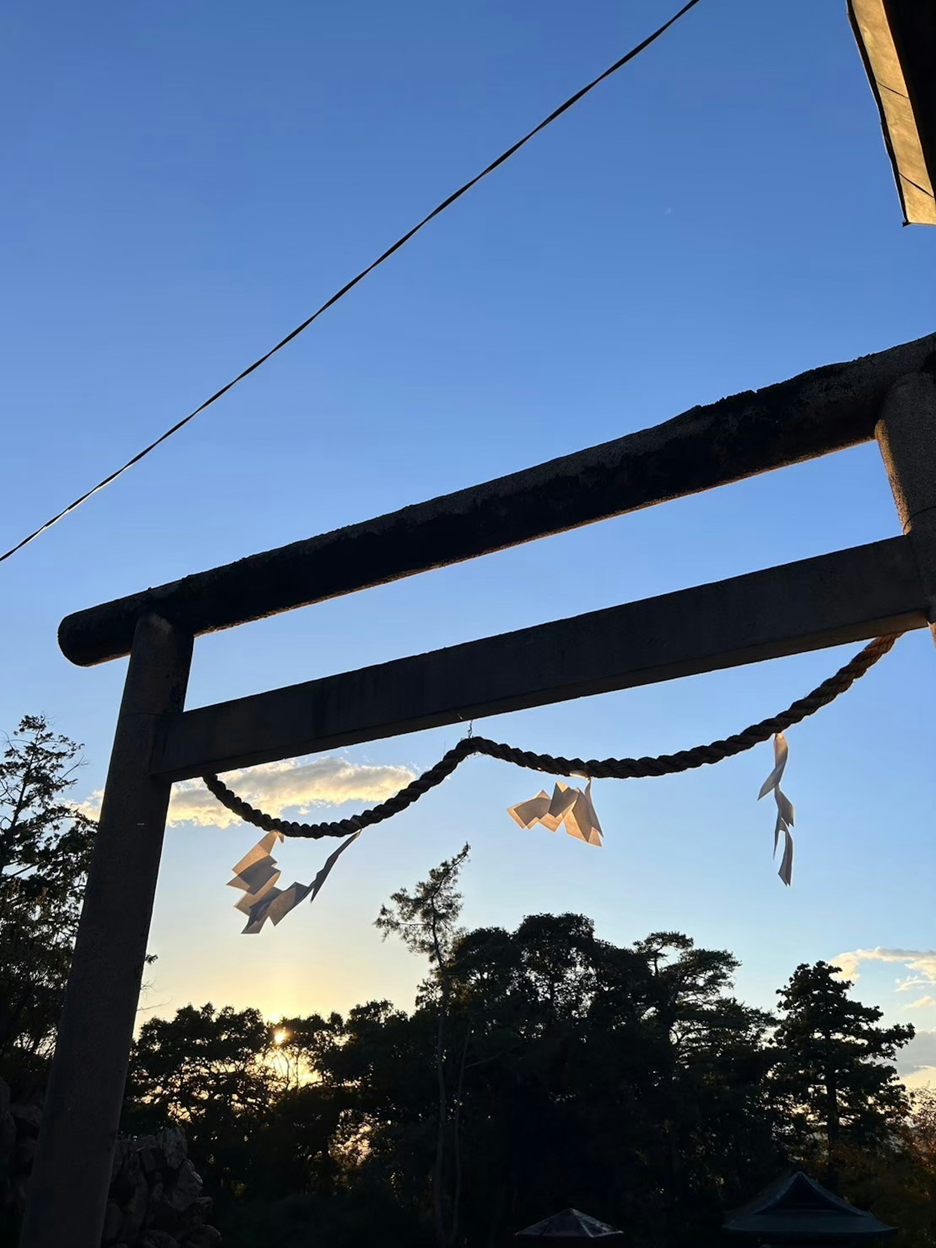 Szene eines Torii unter einem blauen Himmel mit weißen Shide, die im Wind wehen