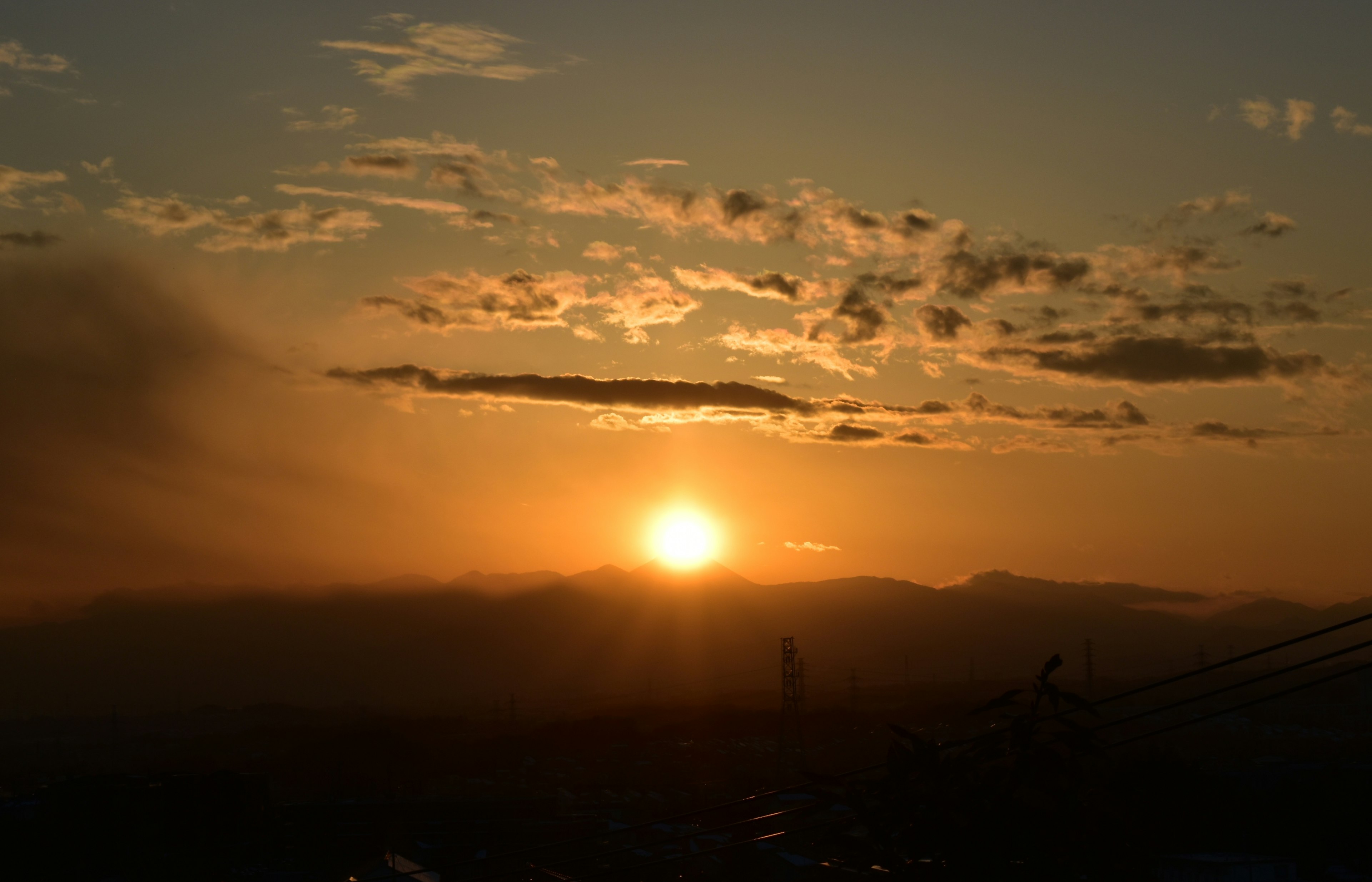 Eine schöne Landschaft des Sonnenuntergangs, der zwischen Bergen versinkt, Wolken färben den Himmel