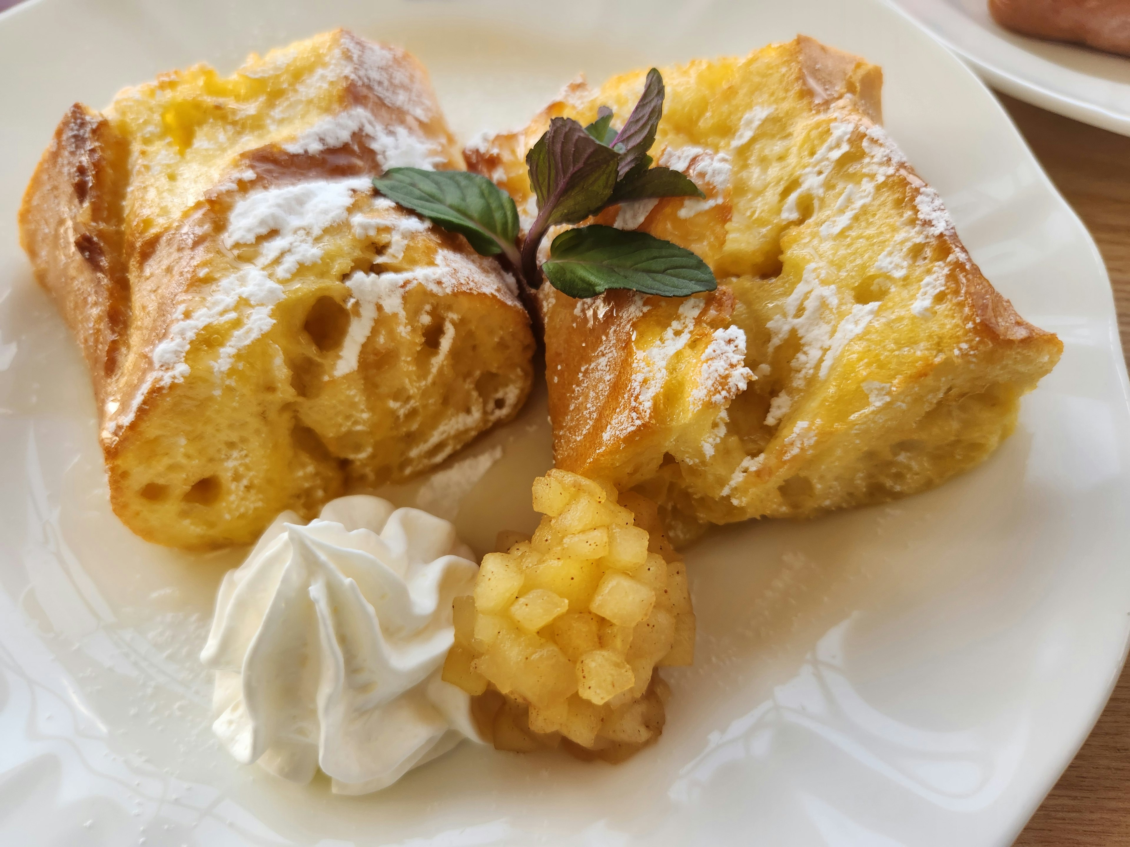 Pudding au pain moelleux garni de sucre glace et de feuilles de menthe servi dans une assiette