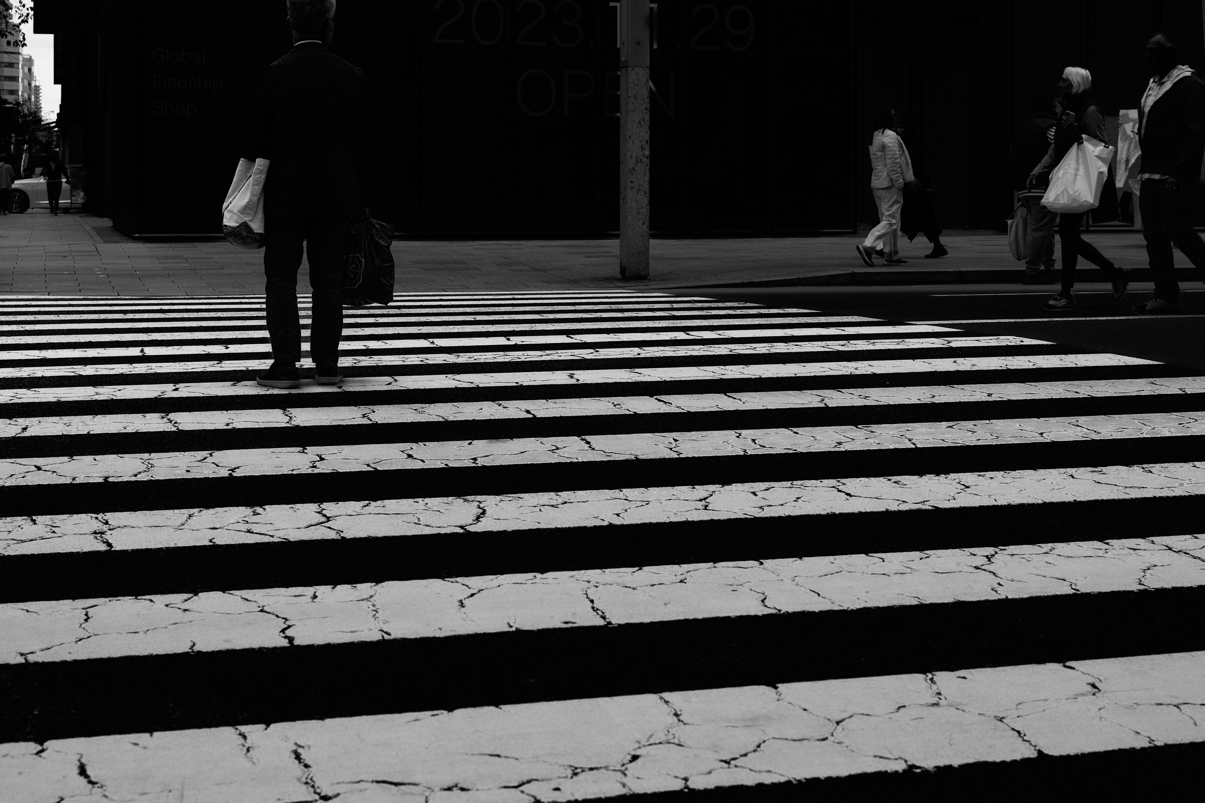 白と黒の横断歩道を渡る人のシルエット