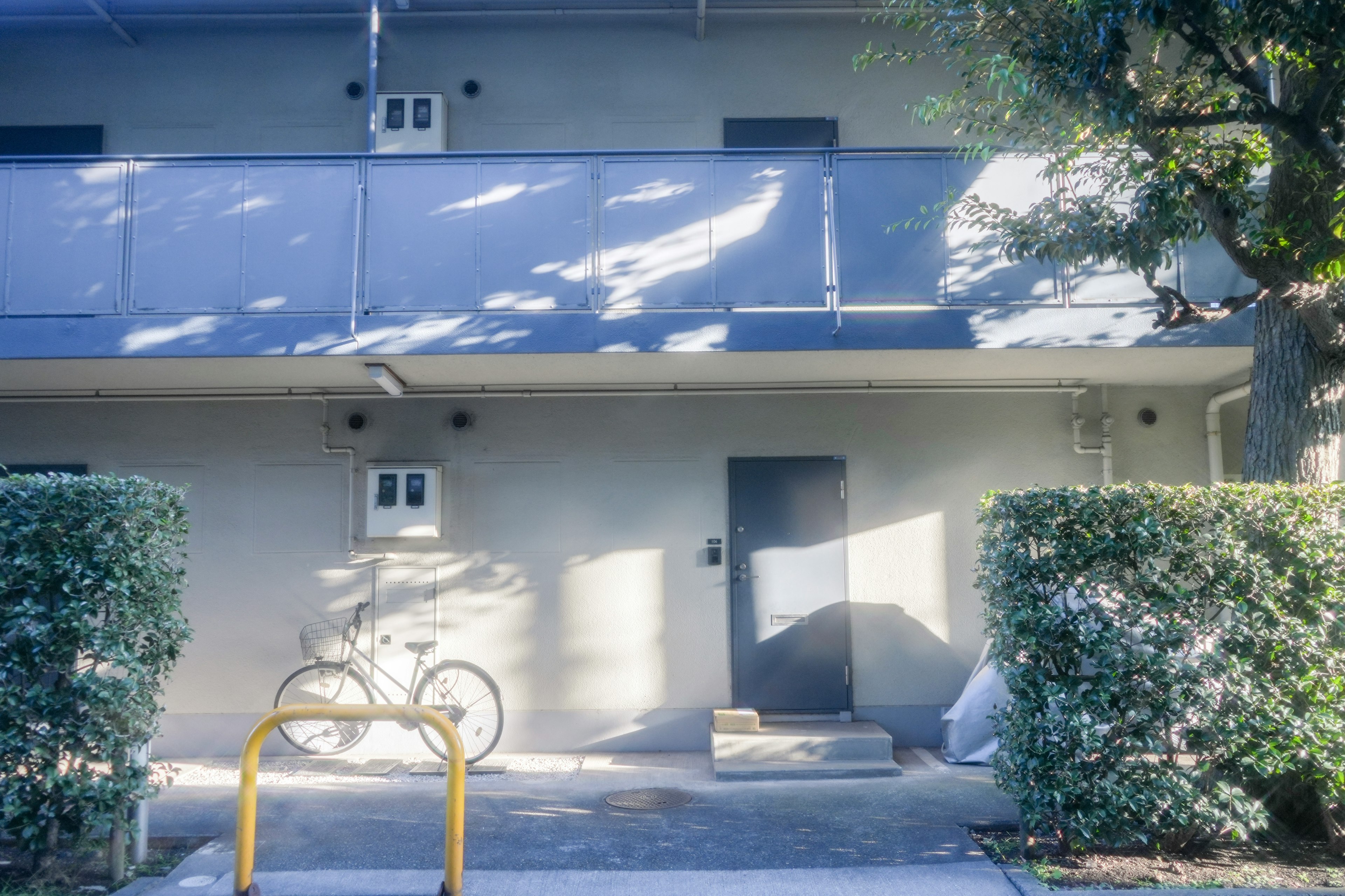 Graue Apartmentfassade mit einem gelben Fahrradständer und einem geparkten Fahrrad