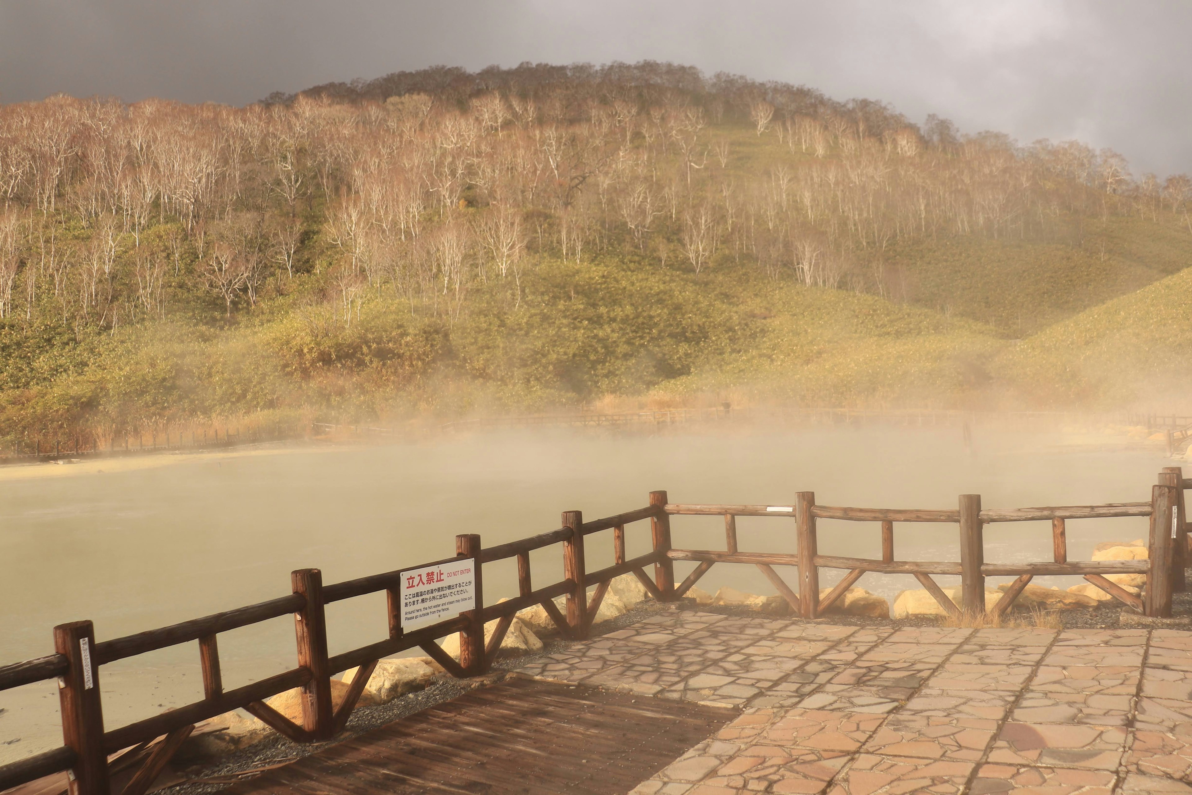 Misty lake view with wooden pier and hills in the background