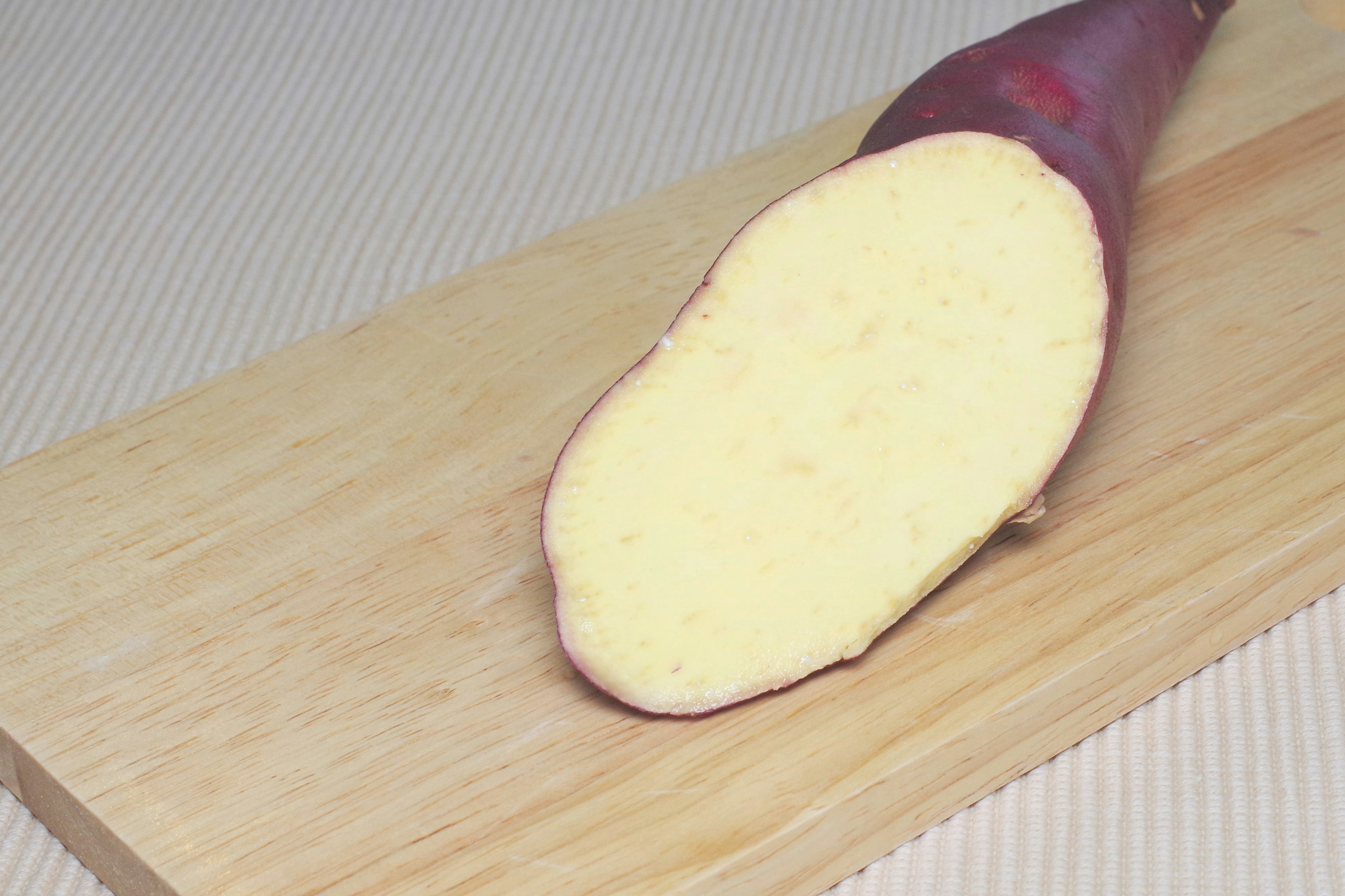 Cut sweet potato placed on a wooden cutting board