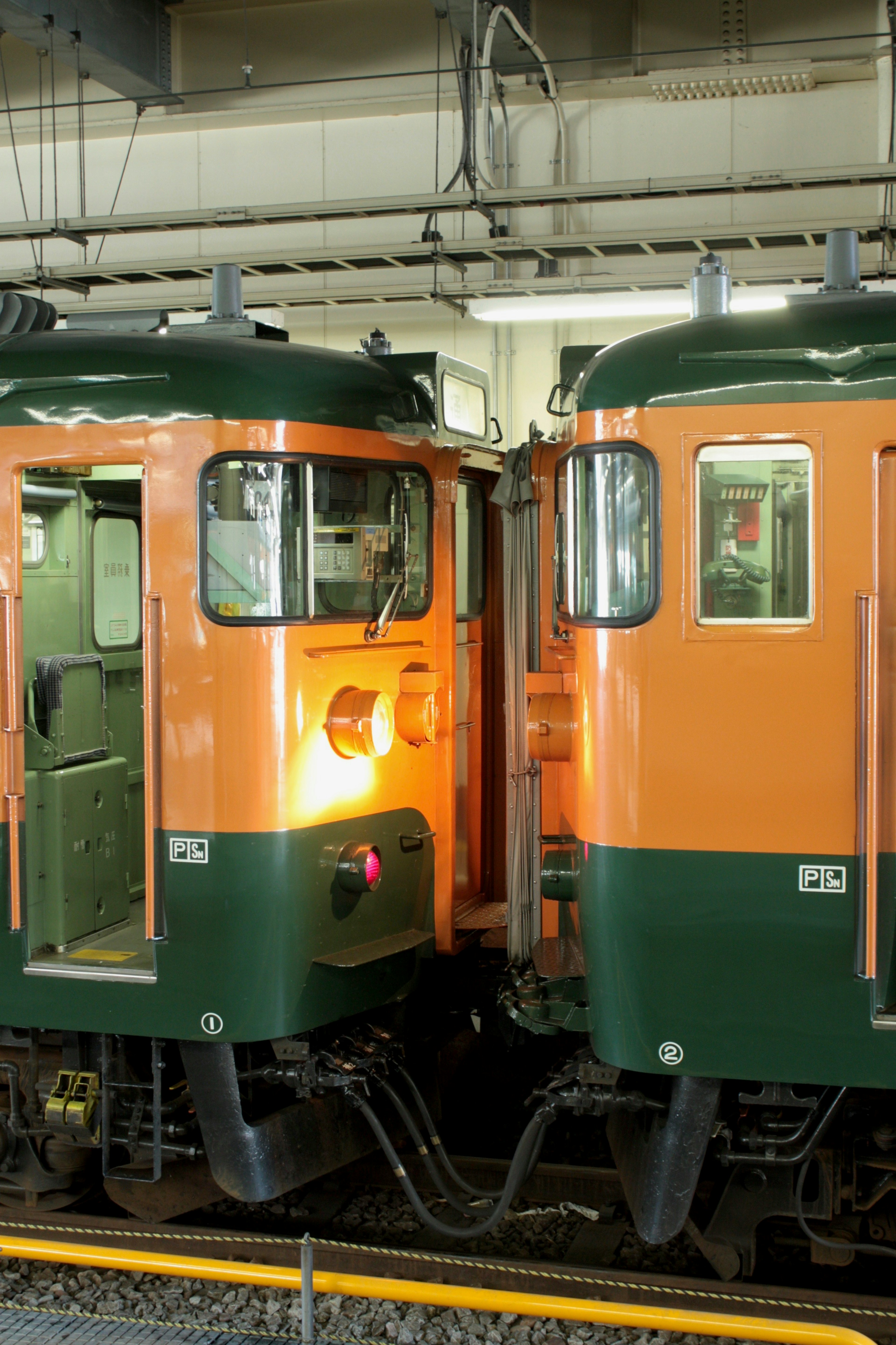 Two train fronts facing each other in green and orange colors