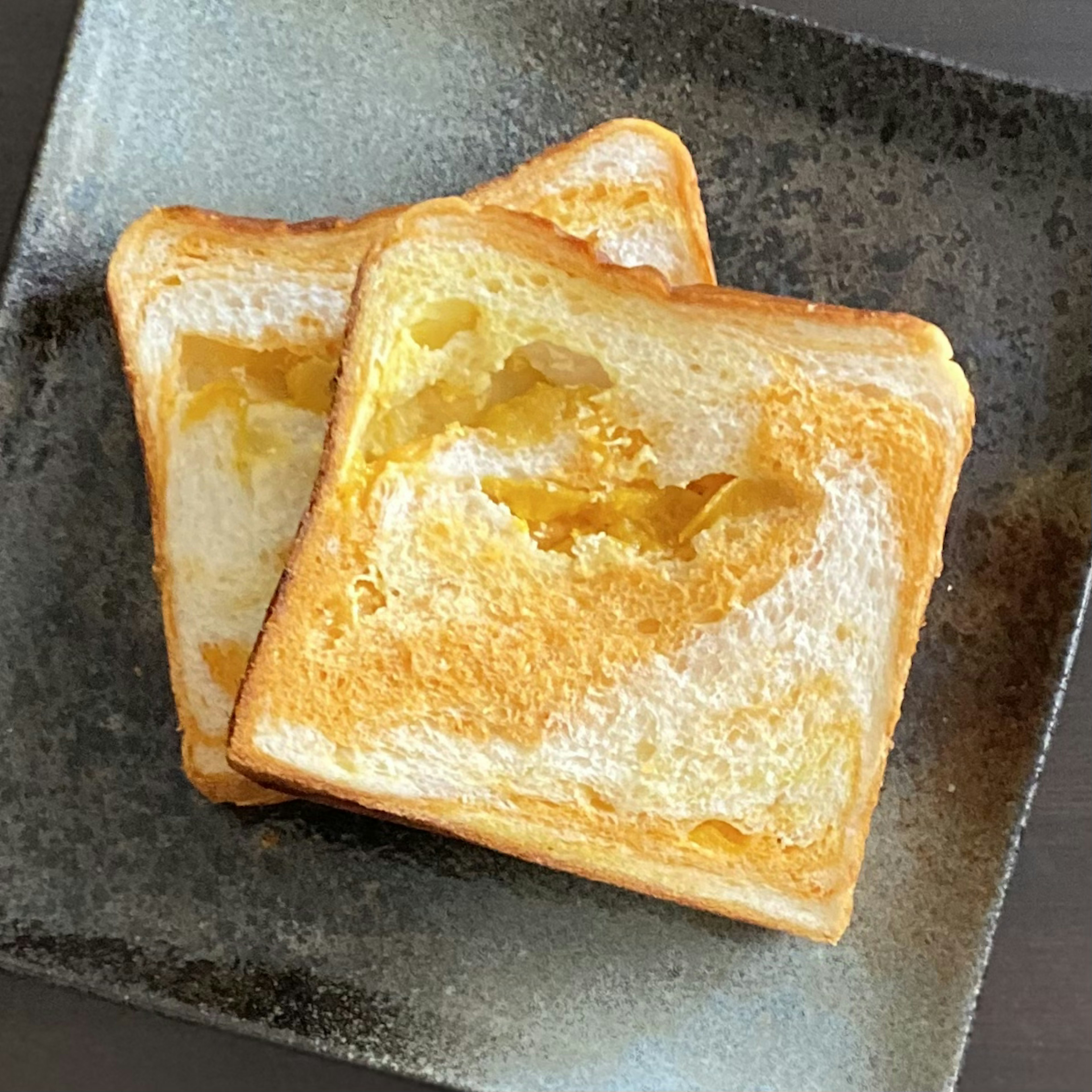 Dos rebanadas de pan tostado con bordes dorados en un plato negro