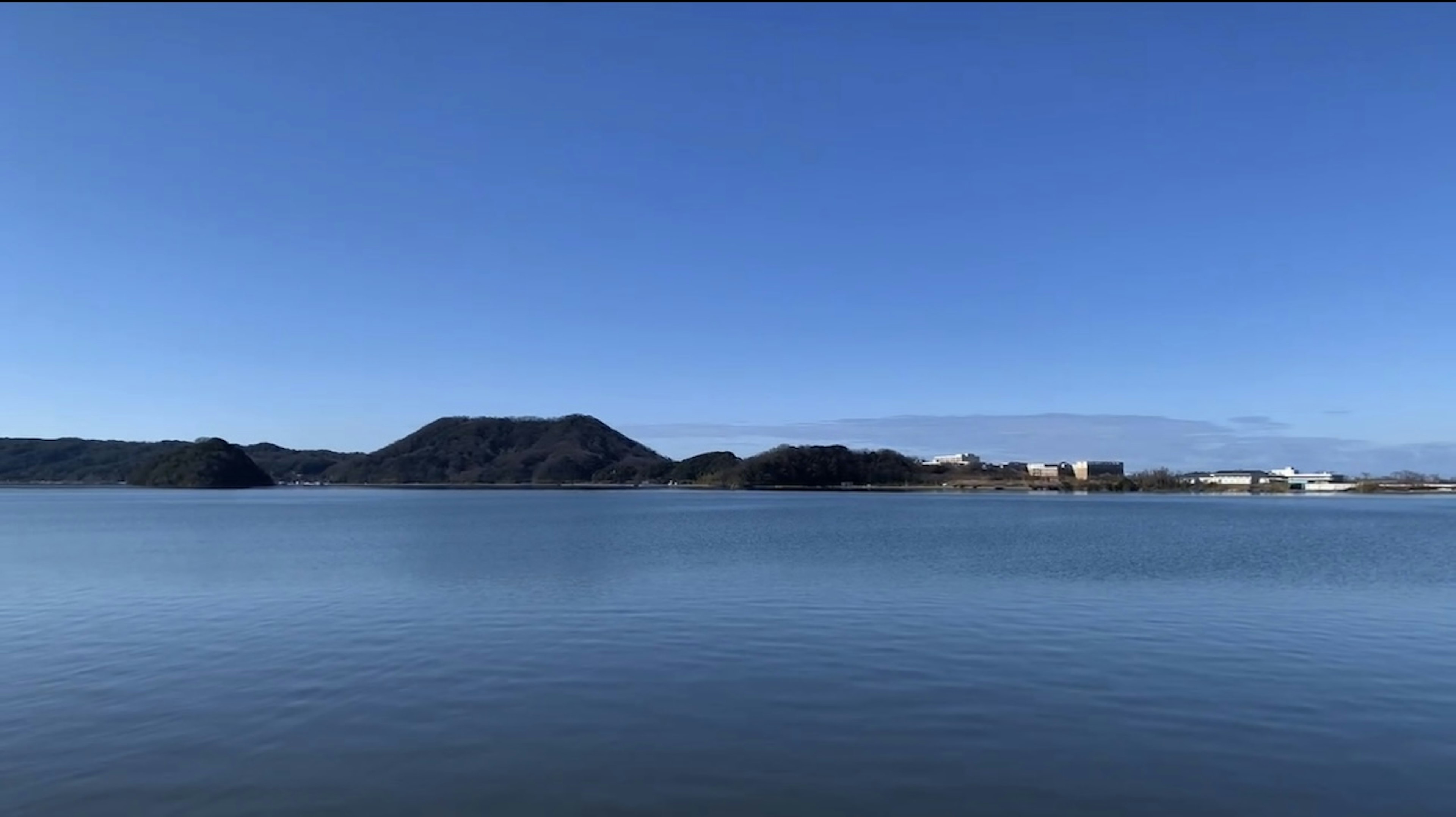 Calm lake and mountain landscape under blue sky