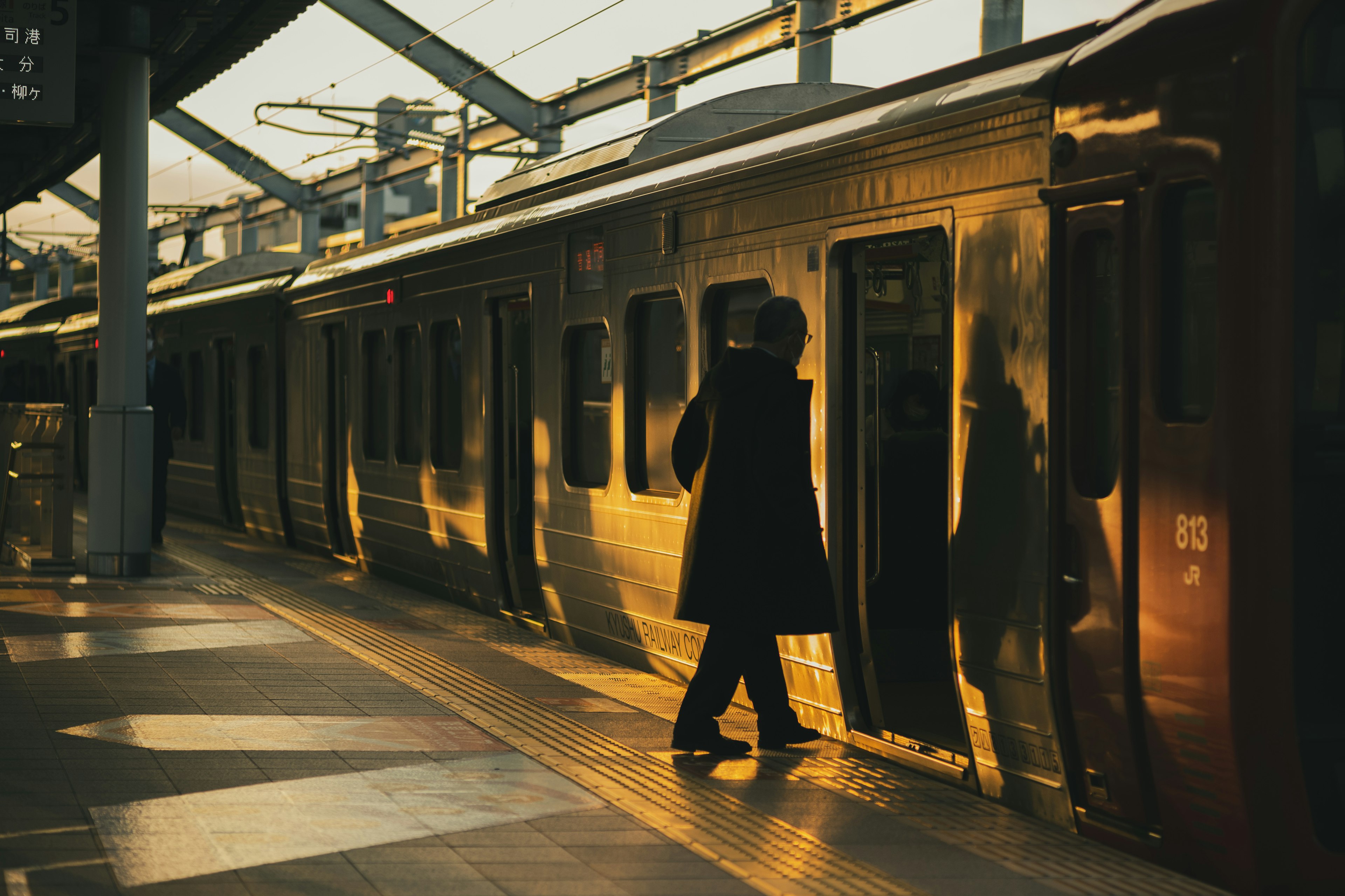 夕陽の中で電車のドアに近づく人物 駅のプラットフォームの景色