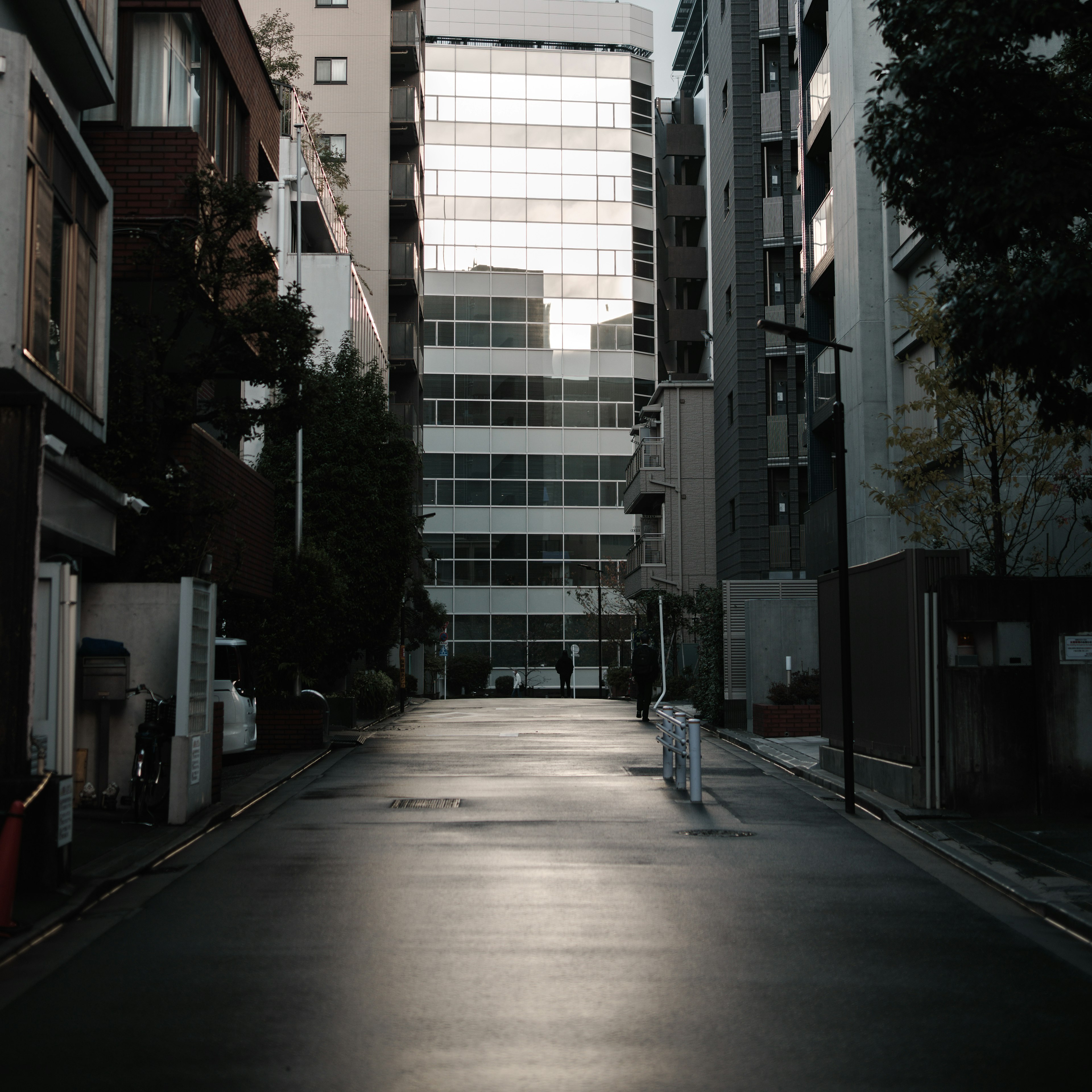 Strada stretta con un edificio in vetro che riflette la luce