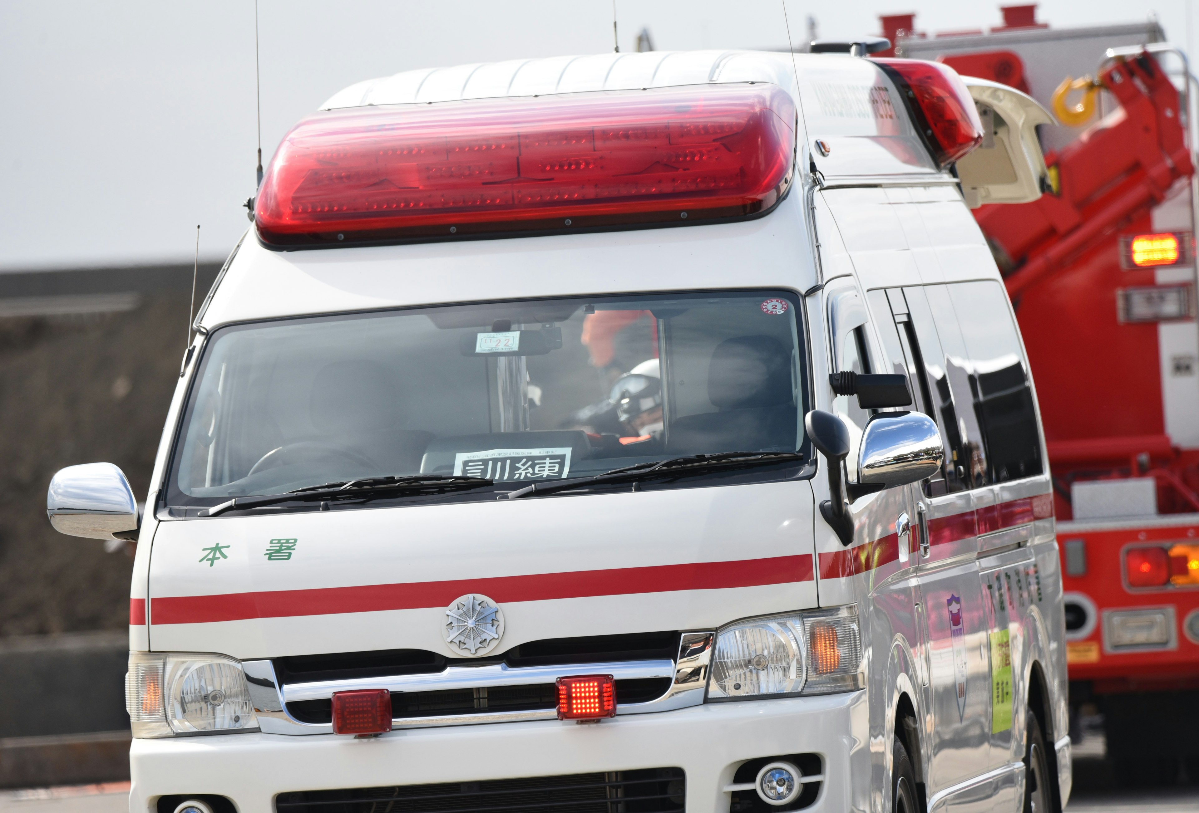 An ambulance with flashing red lights driving on the road