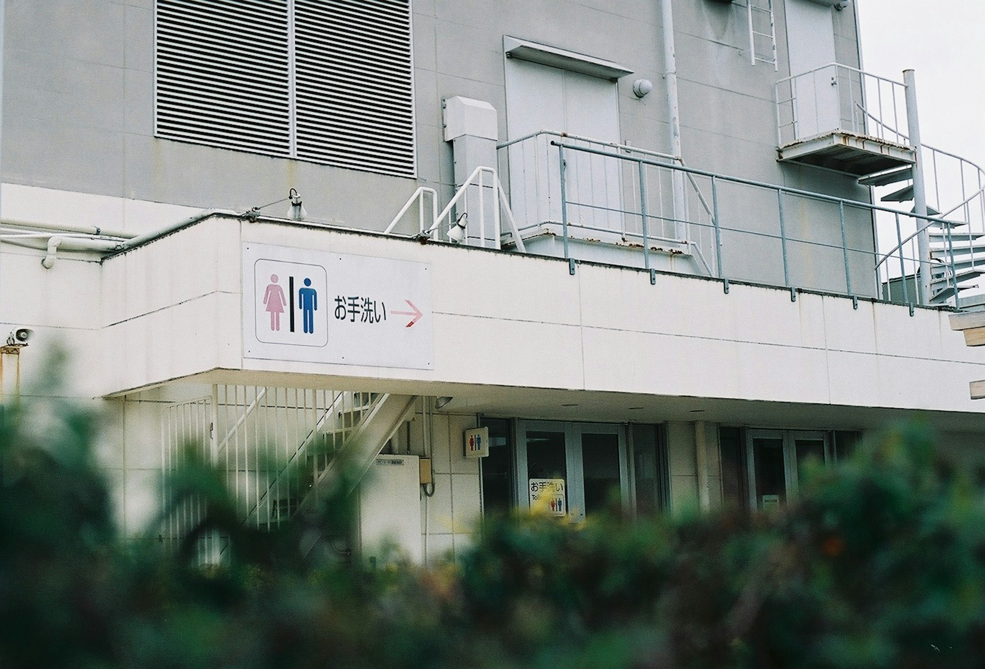 Exterior of a white building featuring gender restroom signs