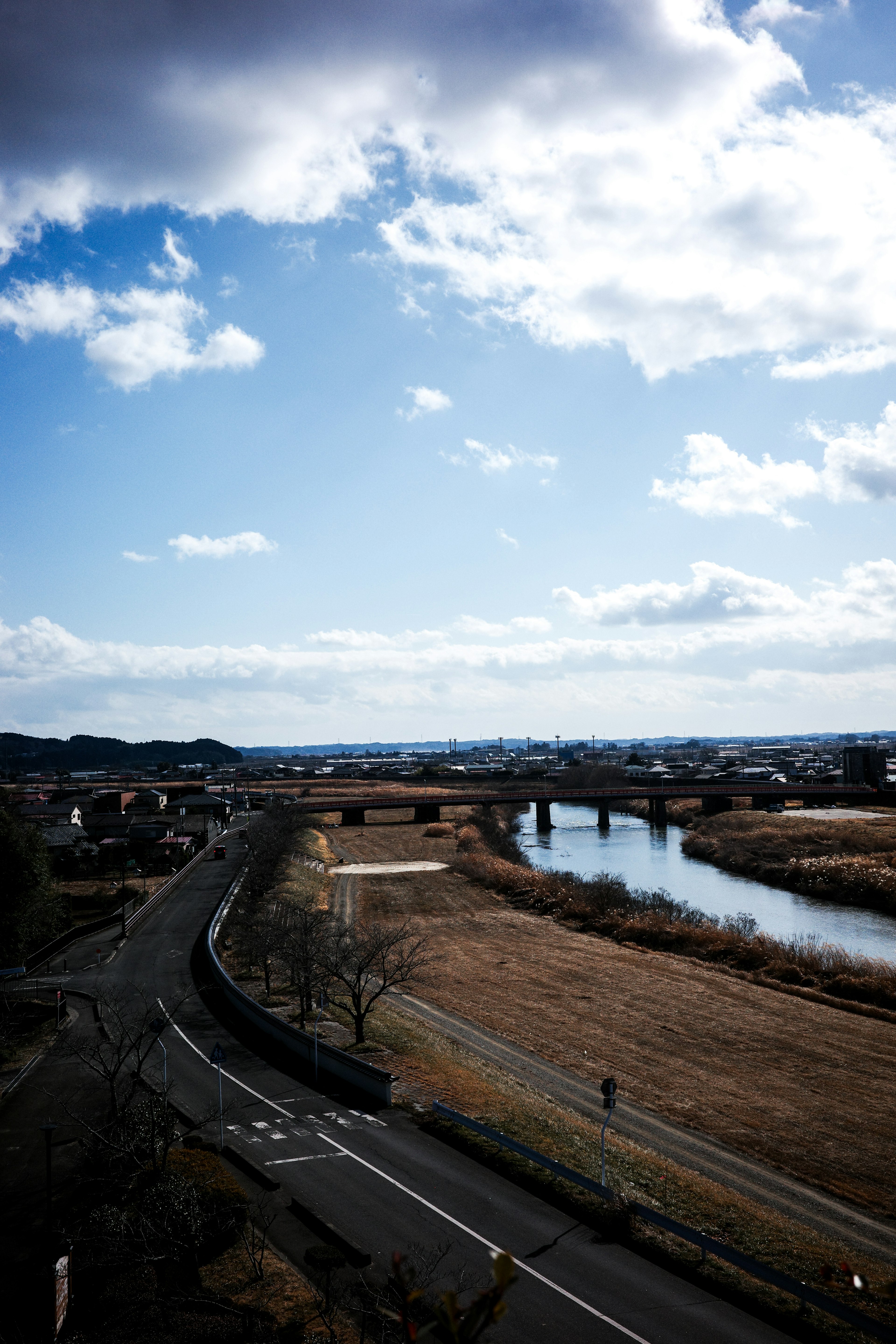 Landschaft mit einem Fluss und einer Straße unter einem blauen Himmel mit Wolken