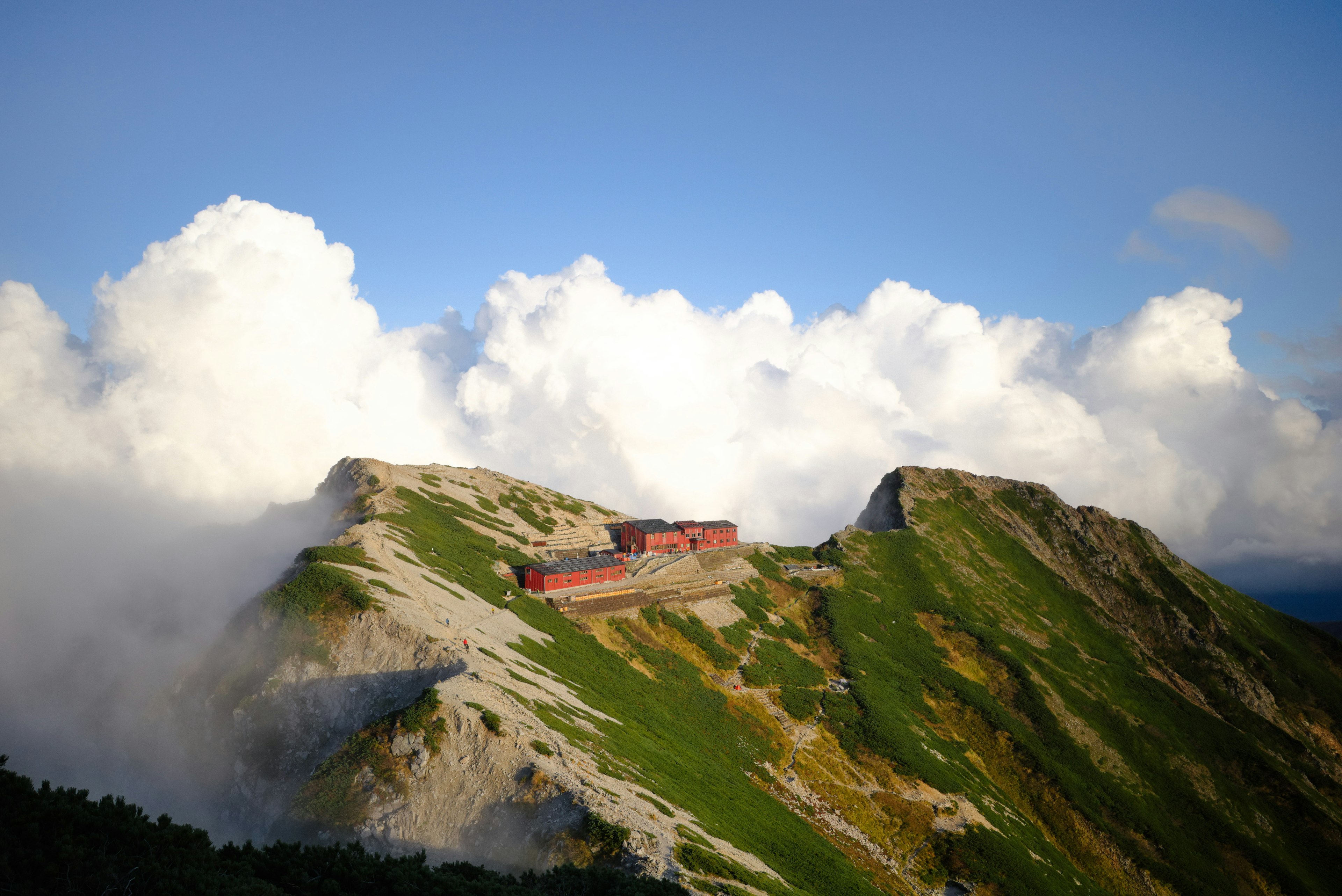 山の頂上にある赤い建物と雲に覆われた風景