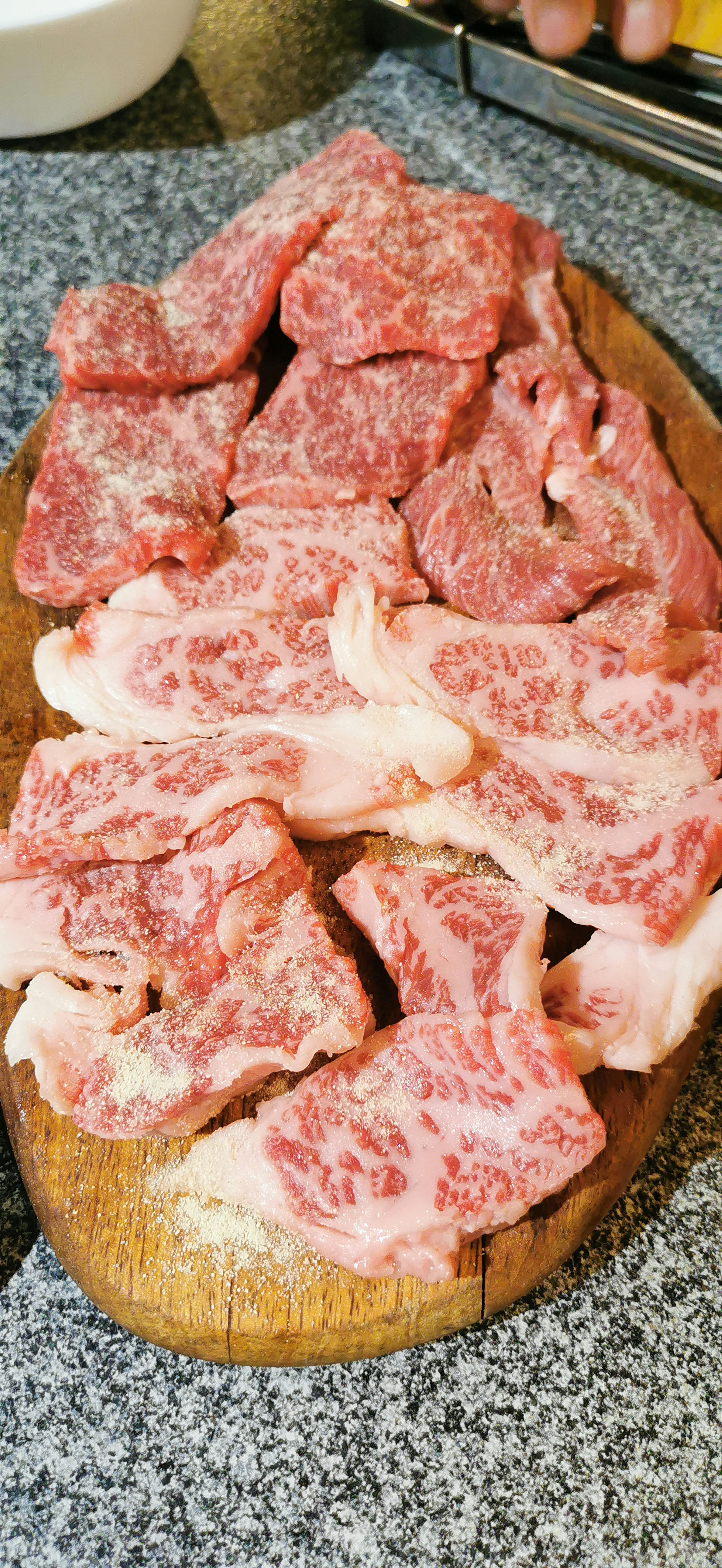 Assorted cuts of marbled meat arranged on a wooden platter