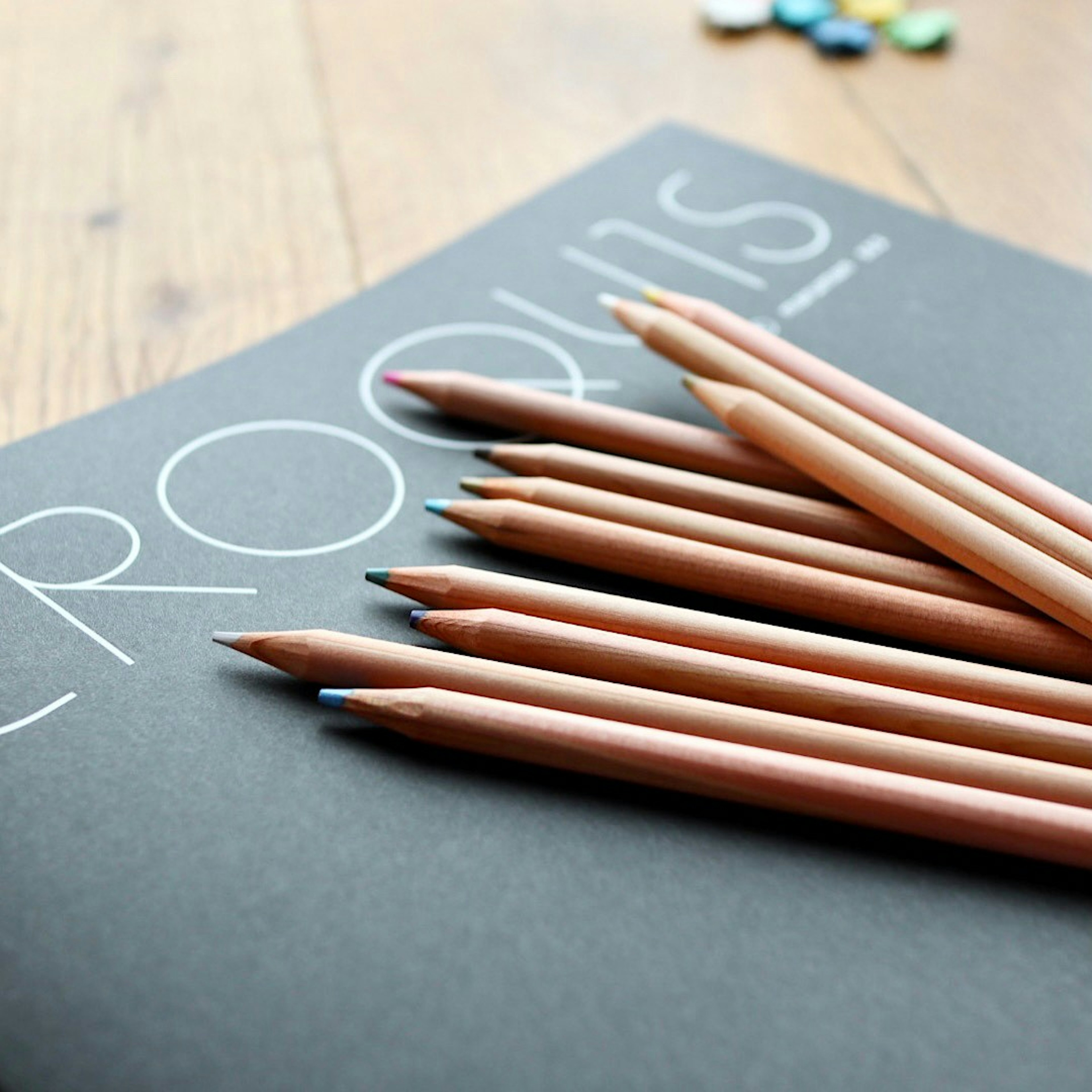 Set of colored pencils on a sketchbook with wooden table background