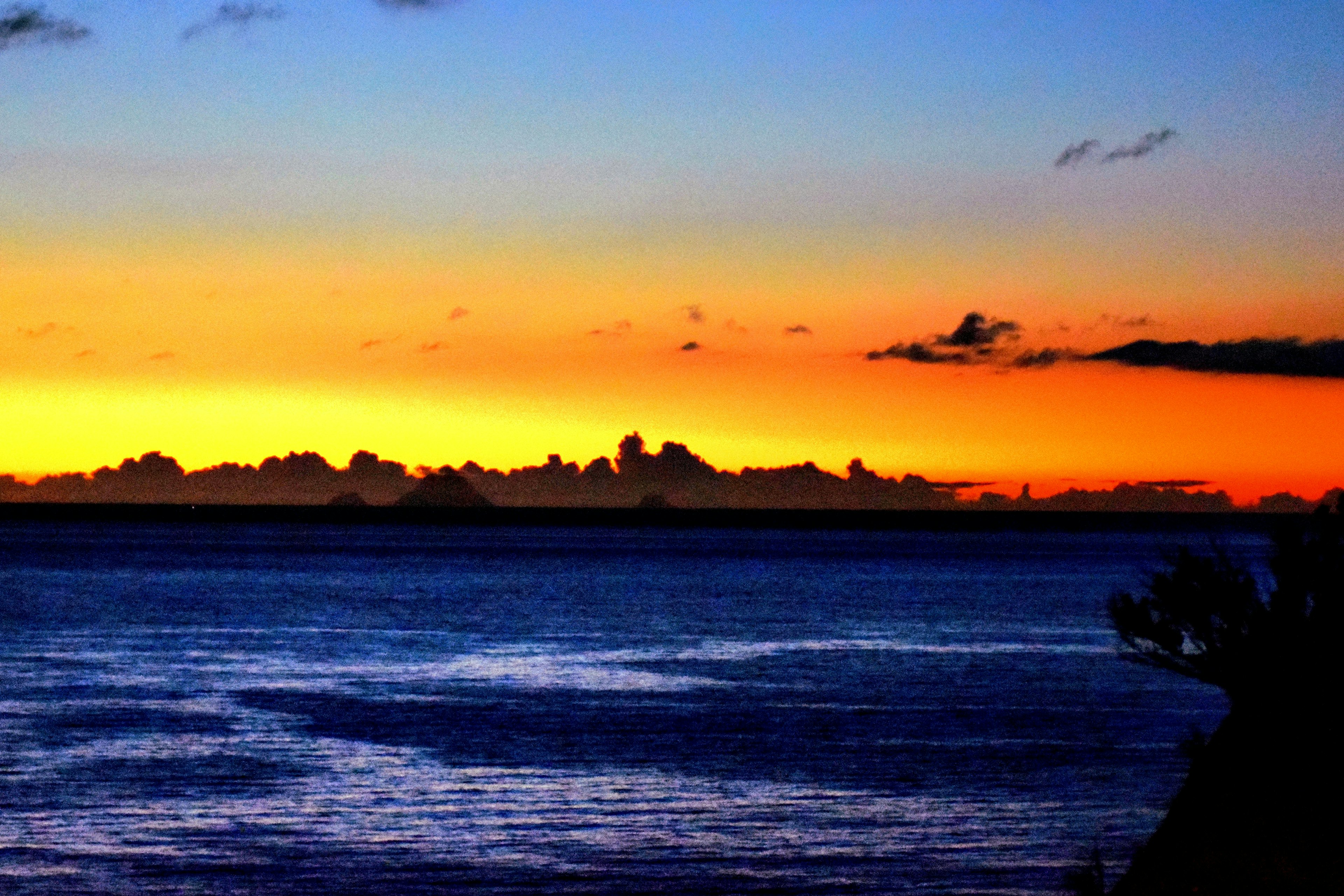 Stupendo tramonto sull'oceano con sfumature blu e arancioni e silhouette di nuvole