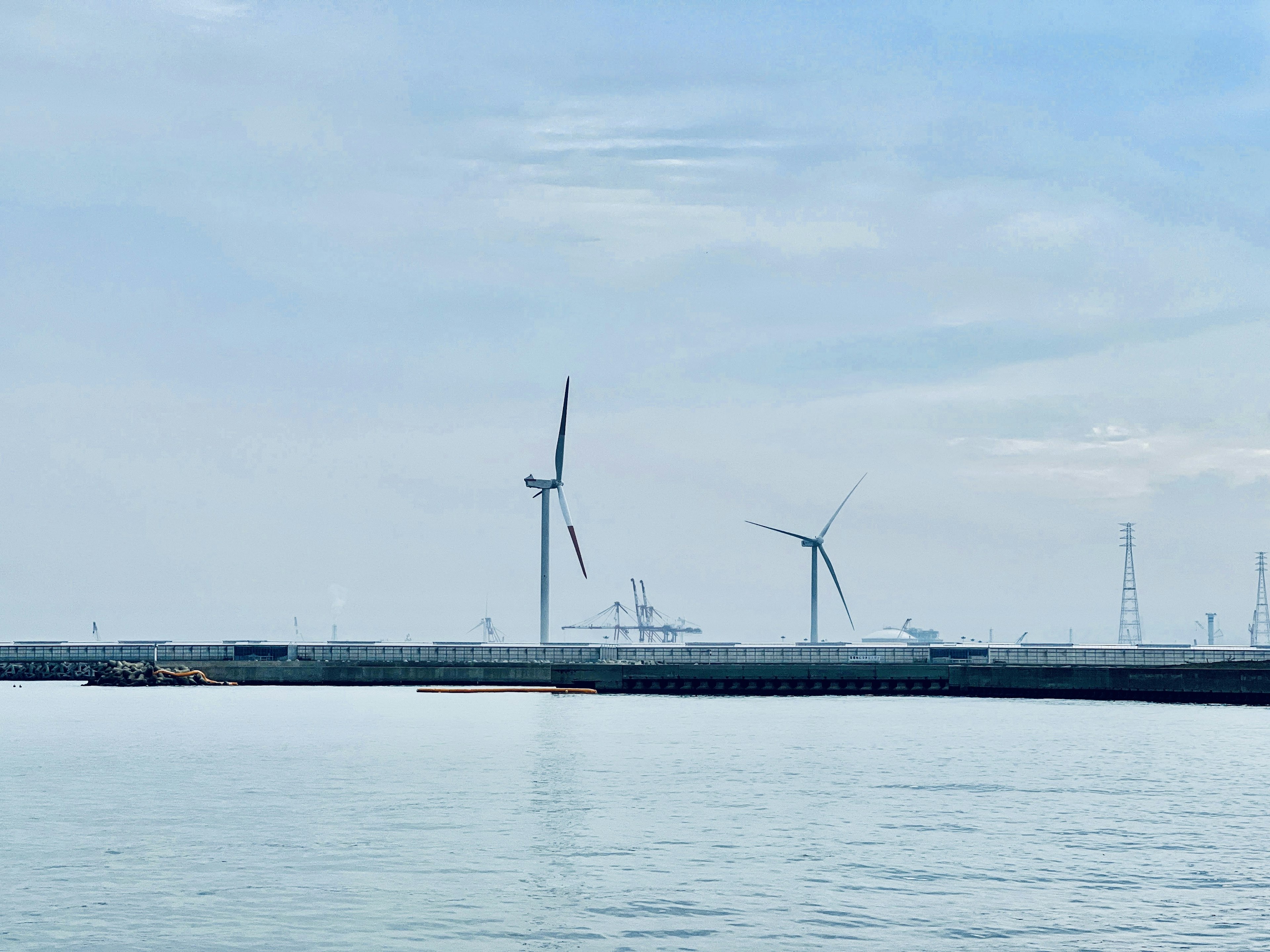 Wind turbines standing on the water with a calm sky