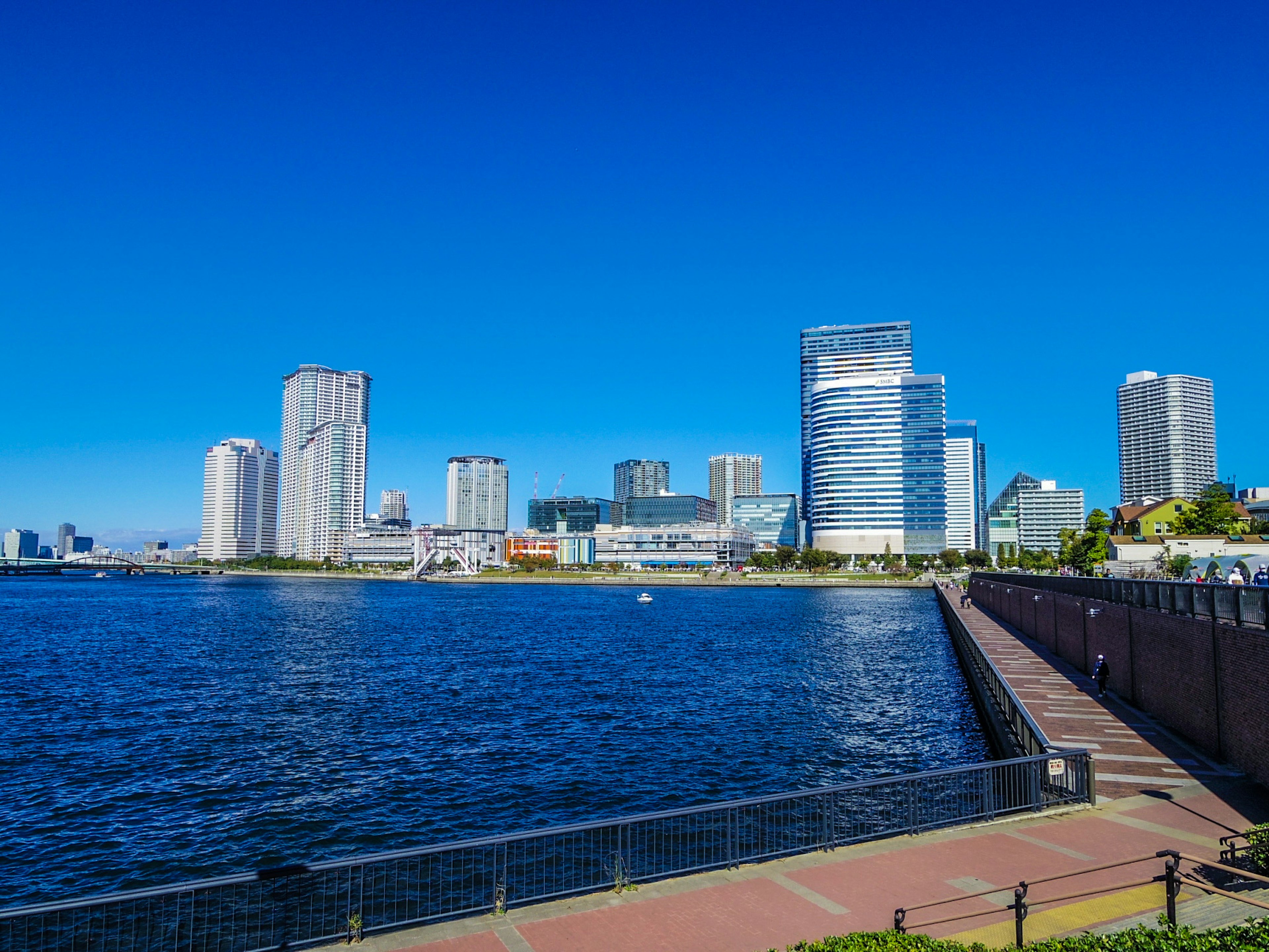 Modern skyscrapers along a waterfront under a clear blue sky