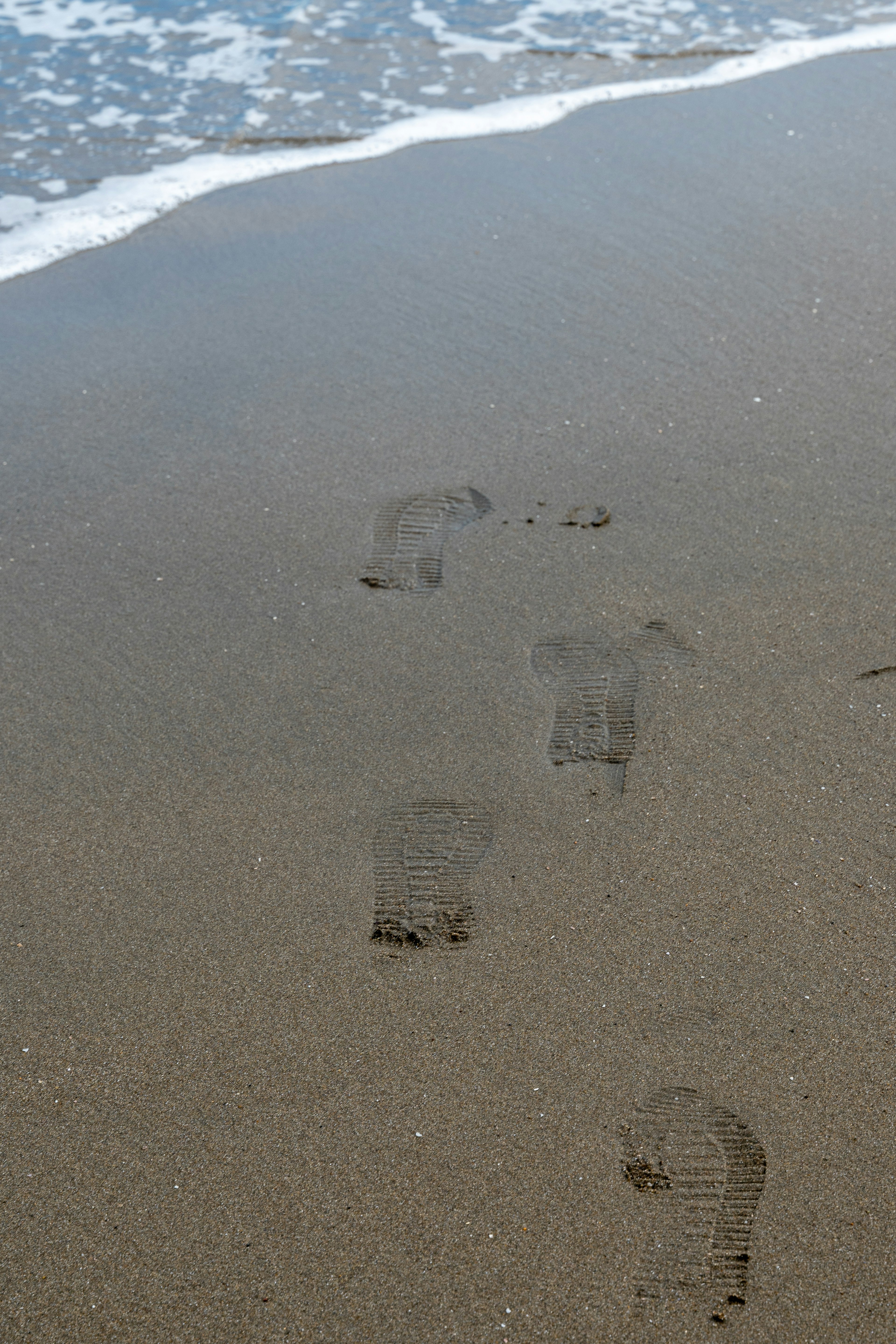 Fußabdrücke im Sand, die von den Wellen gewaschen werden