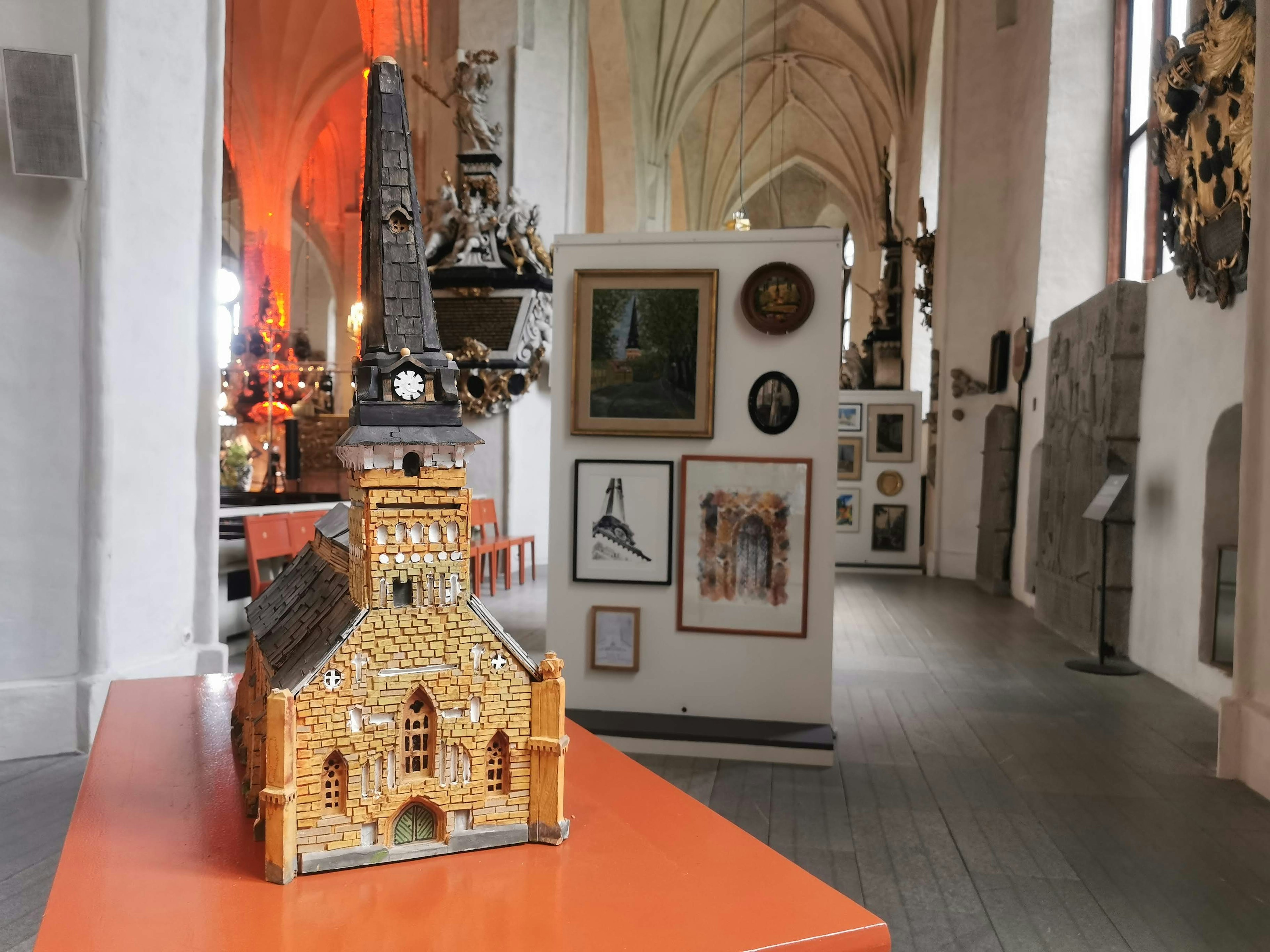 Interior of a museum featuring a miniature church model and various art pieces