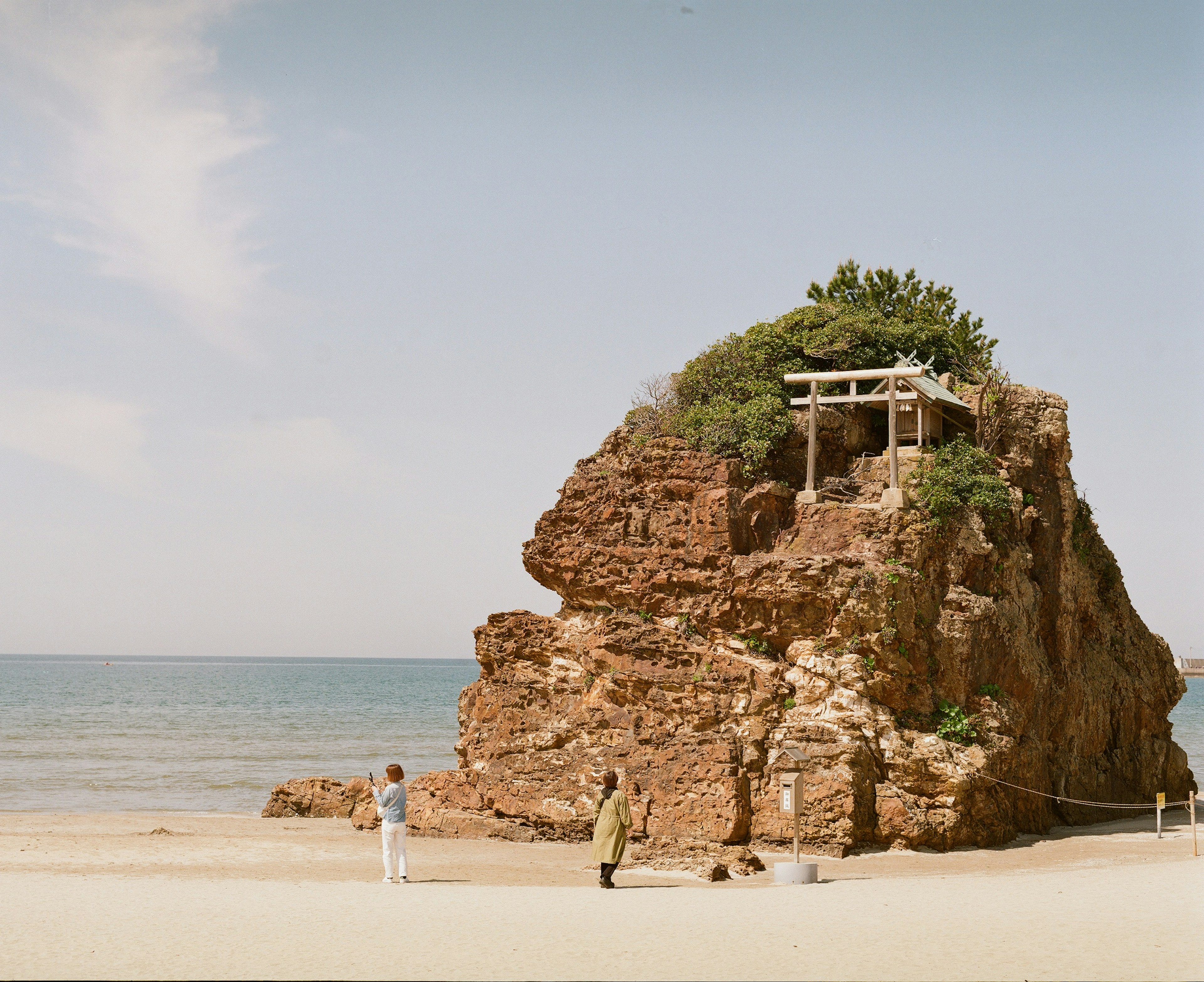 海岸場景，岩石結構上有神社