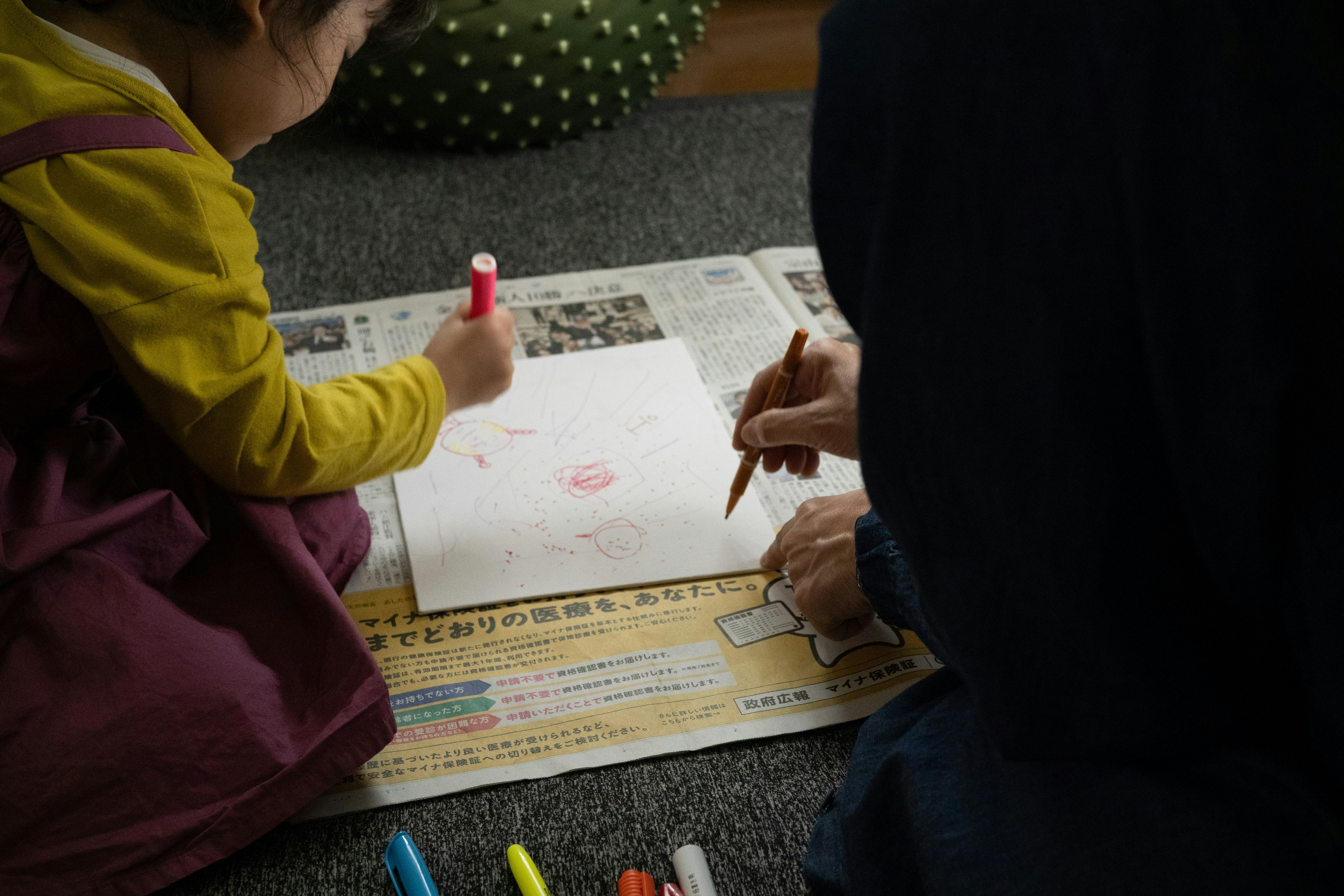 Un niño dibujando con crayones mientras un adulto lo ayuda