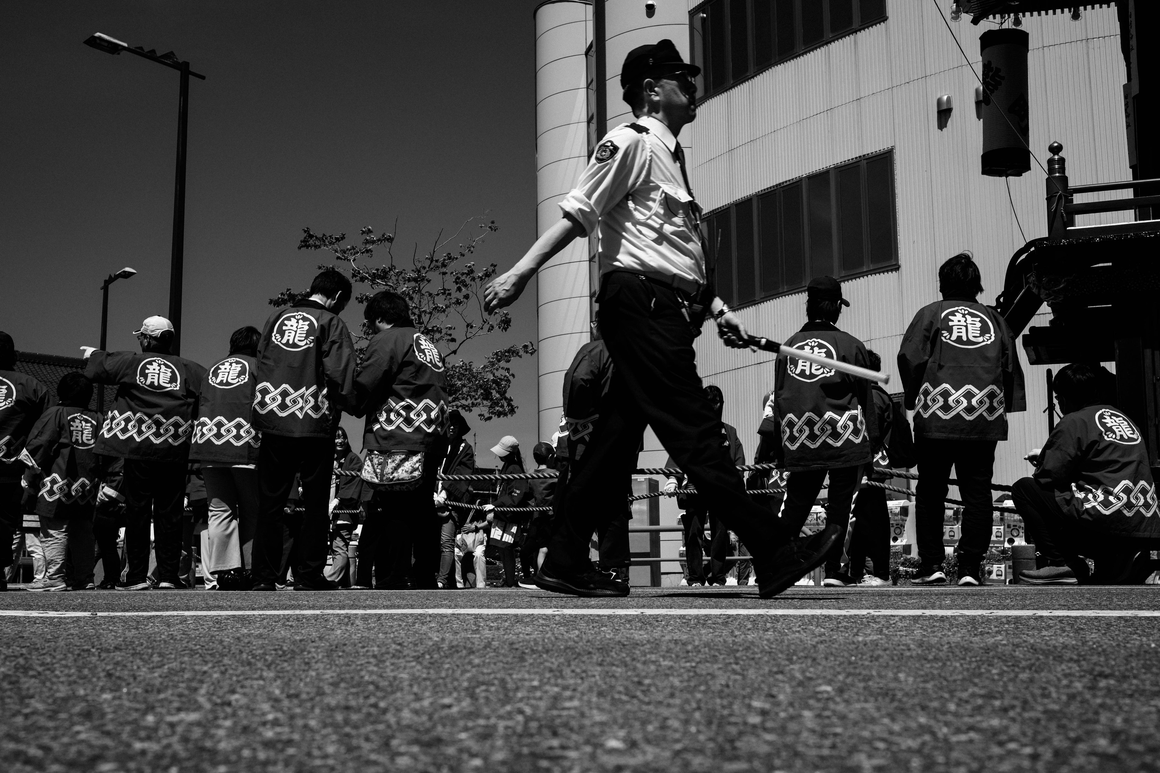 黒白の街中で伝統的な衣装を着た人々が集まっている様子