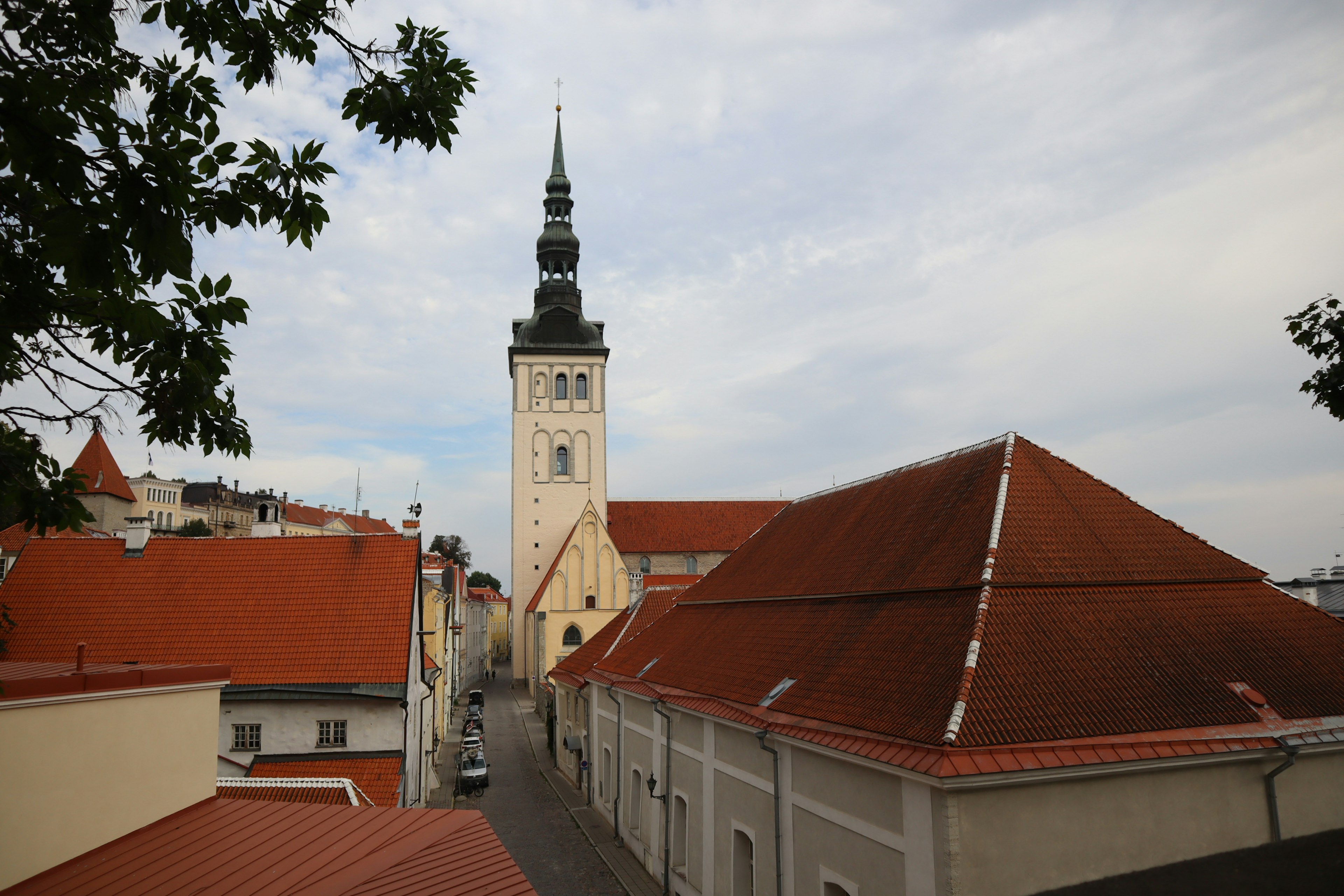 Kirchturm, der über charmante Straßen mit orangen Dächern ragt