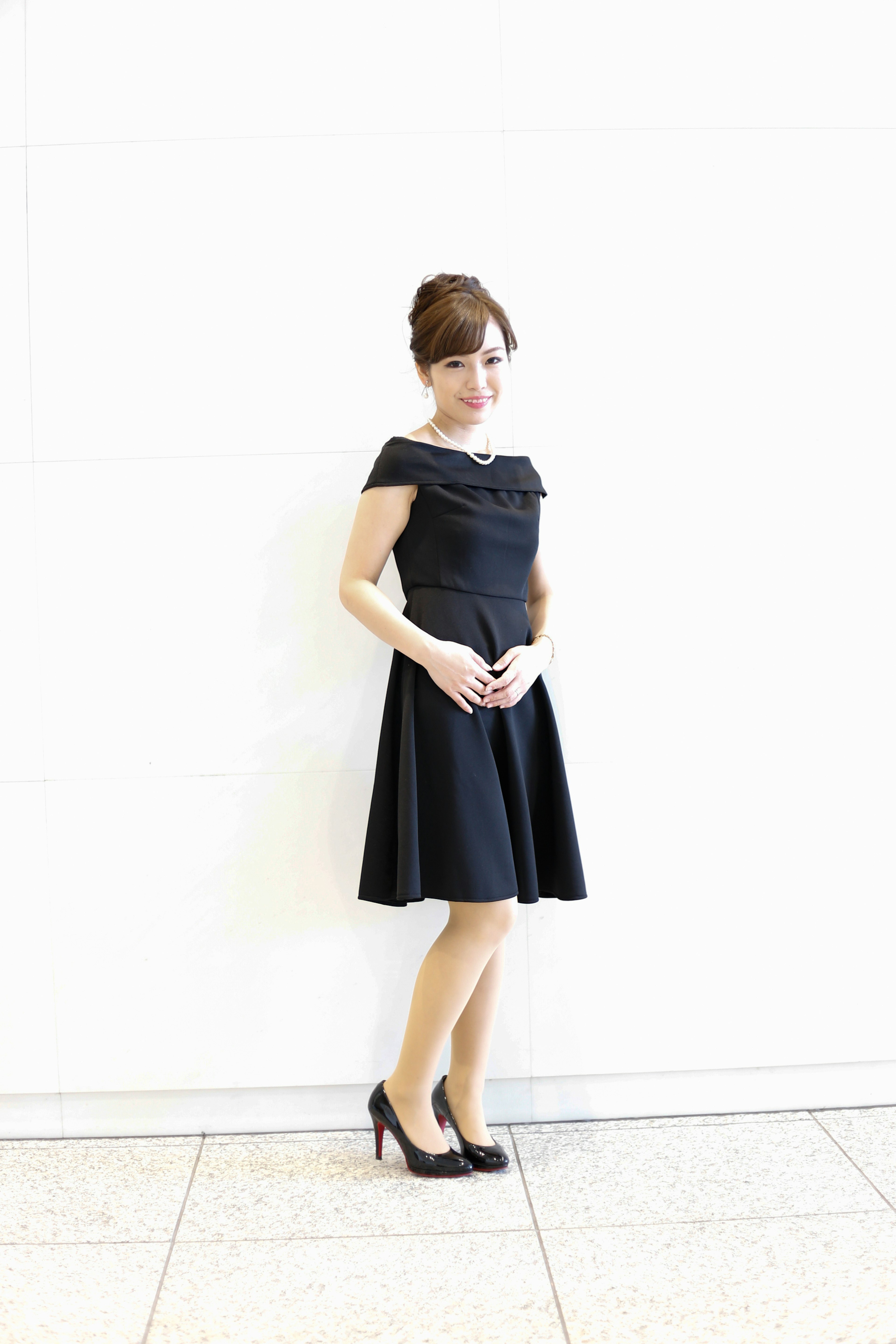 A woman in a black dress standing in front of a white background