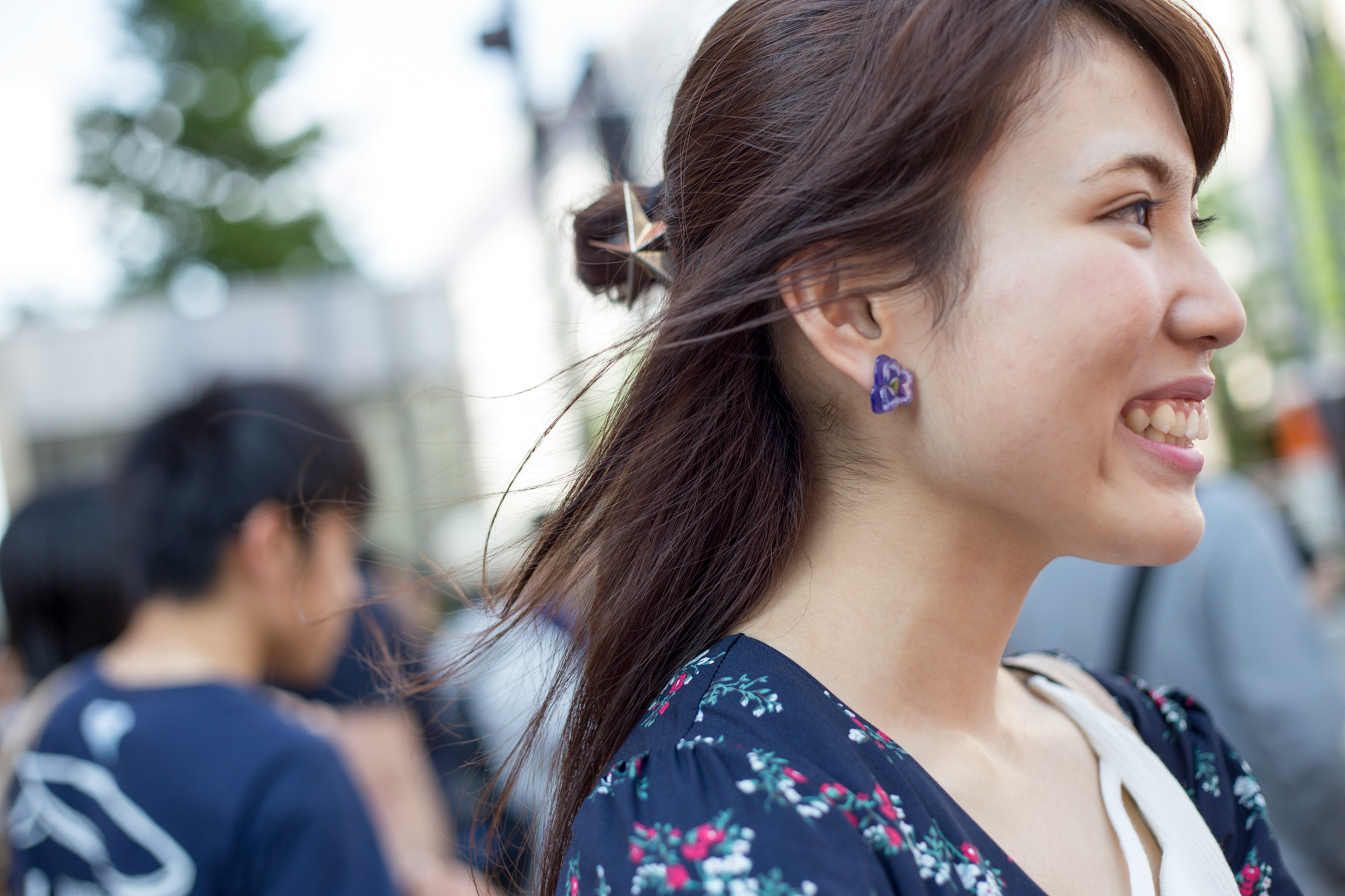 หญิงสาวยิ้มในสภาพแวดล้อมในเมือง โปรไฟล์ด้านข้างและชุดดอกไม้ที่โดดเด่น