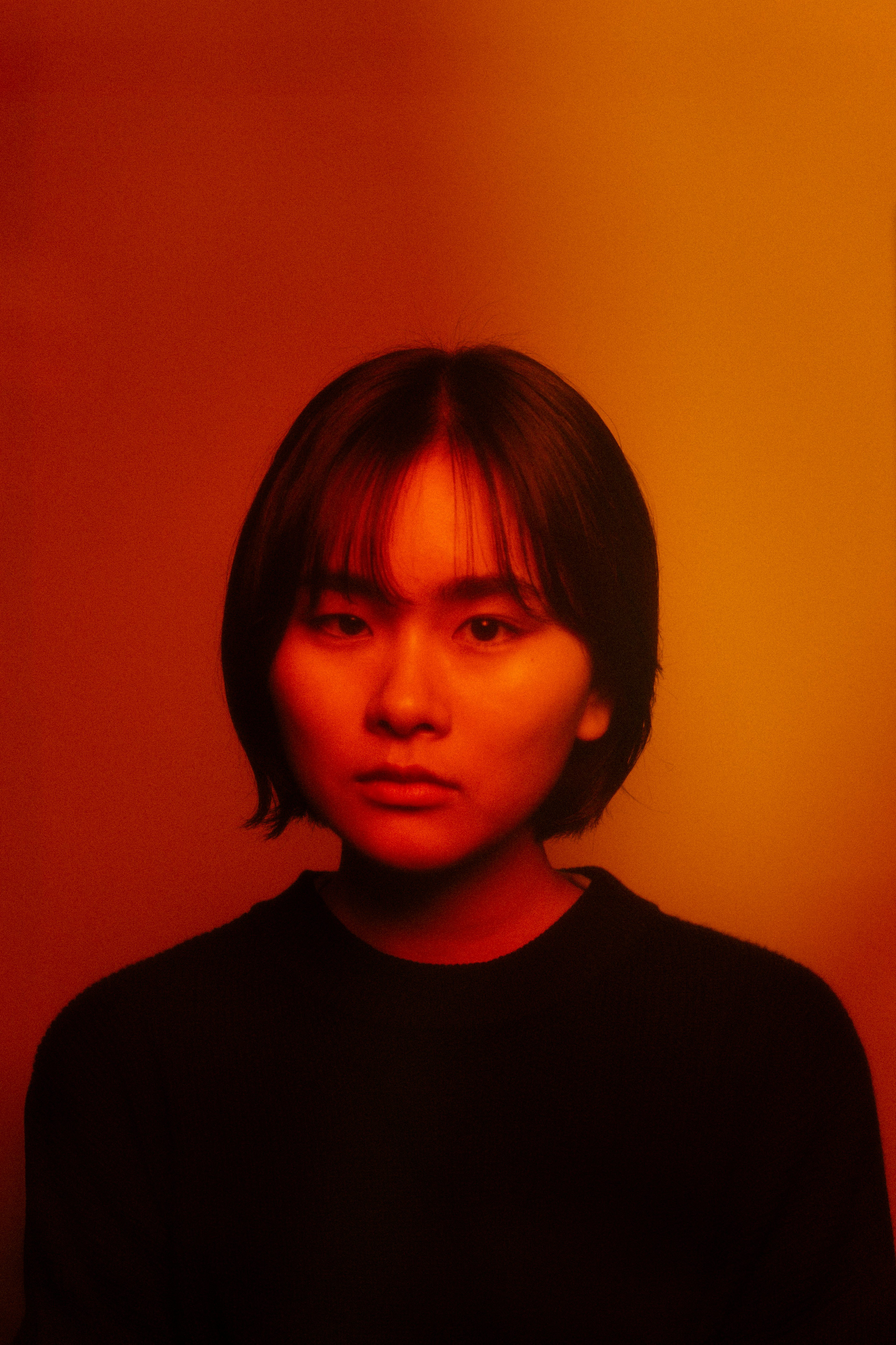 Young person with short hair against a warm orange background