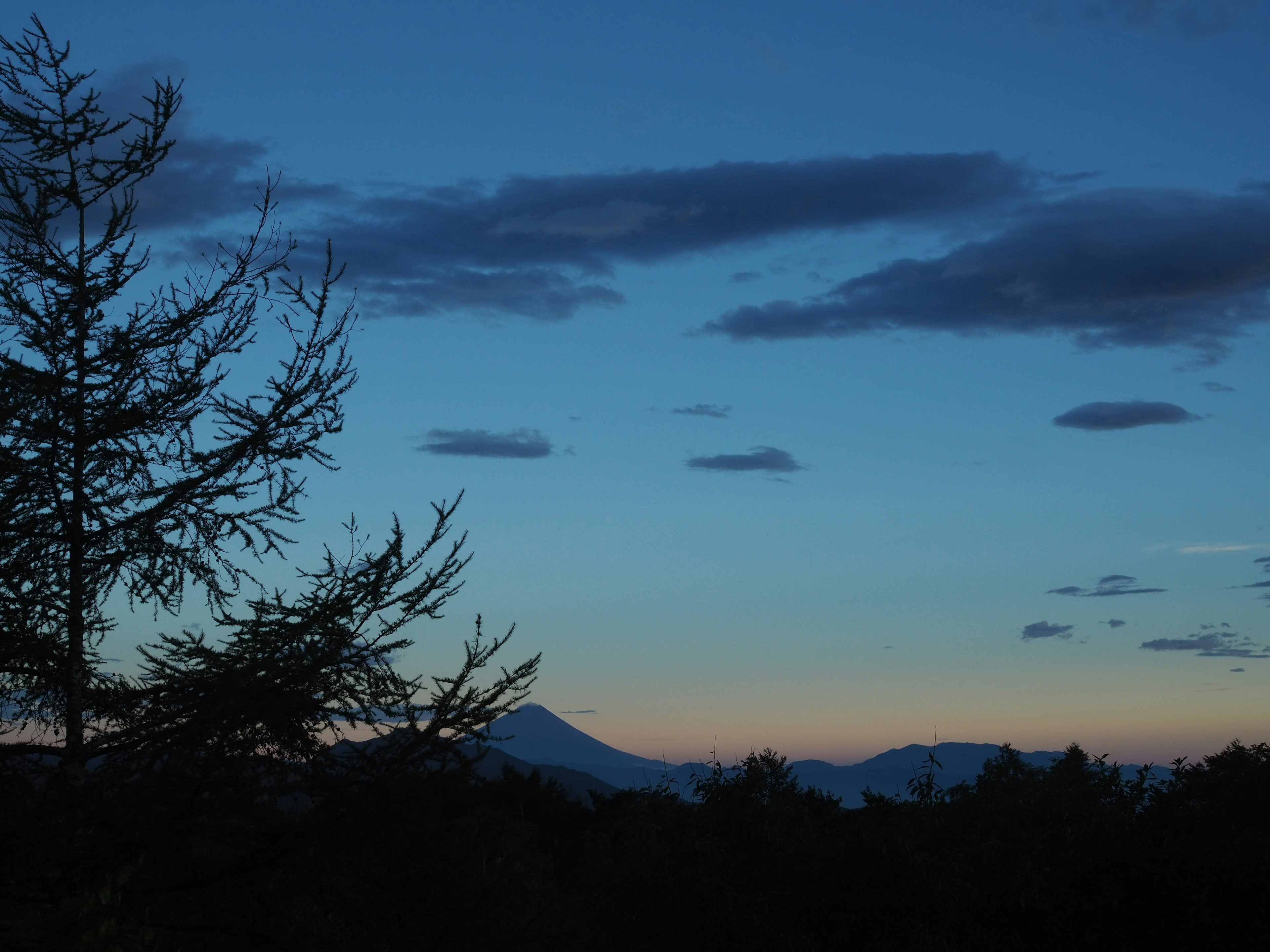 夕暮れの空に浮かぶ雲と山々のシルエット