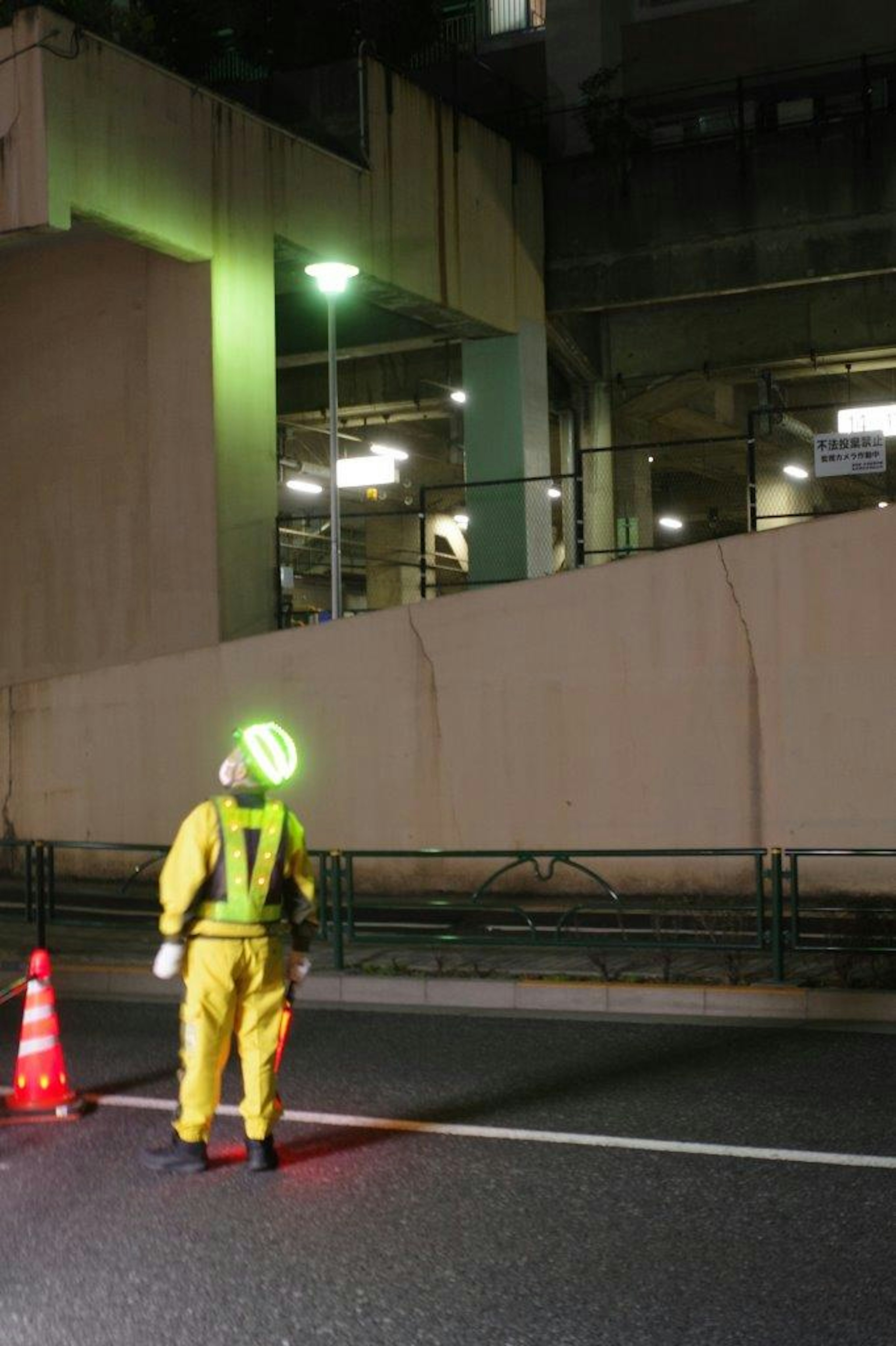 Un travailleur en vêtement jaune dirigeant la circulation la nuit