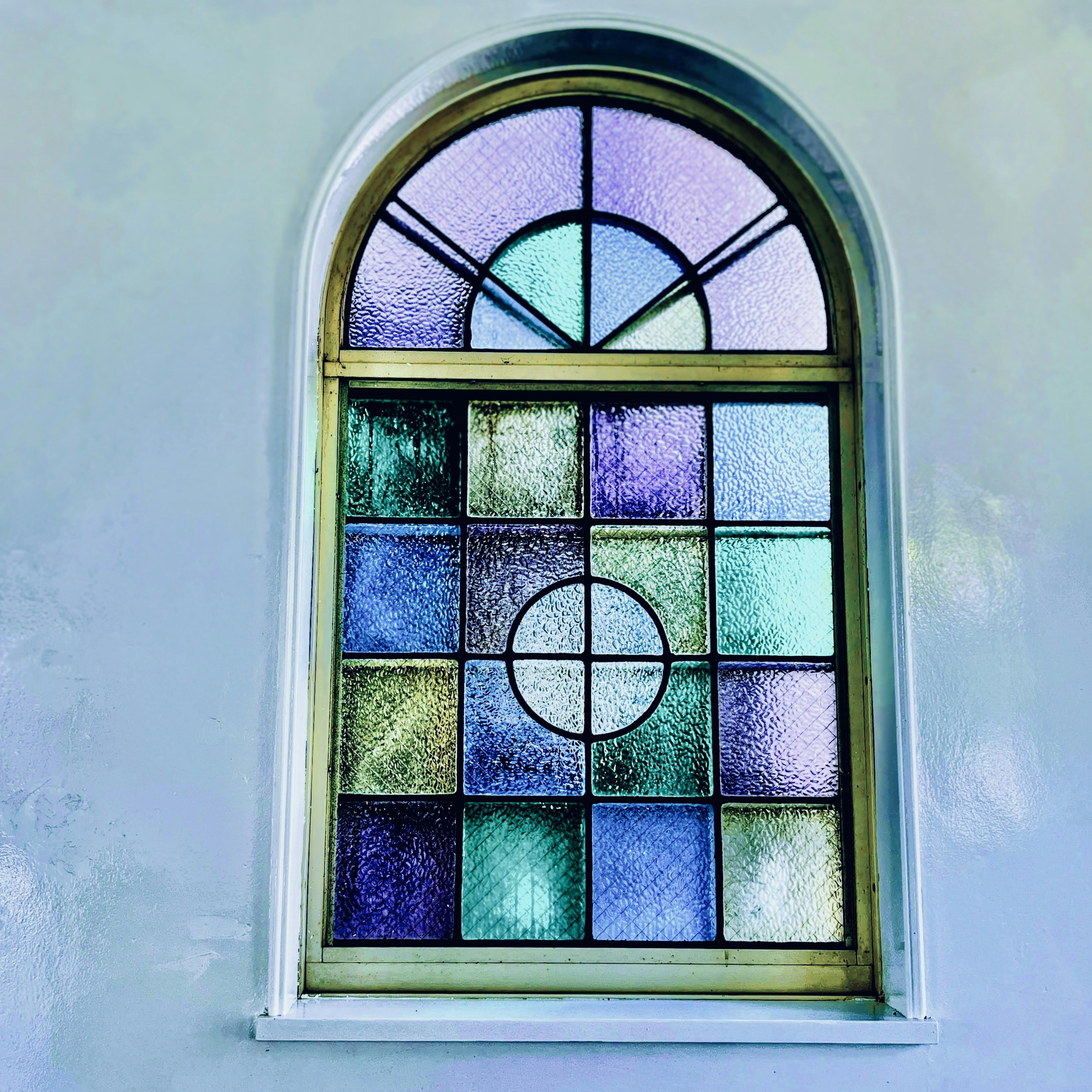 Arched stained glass window featuring blue and purple tiles