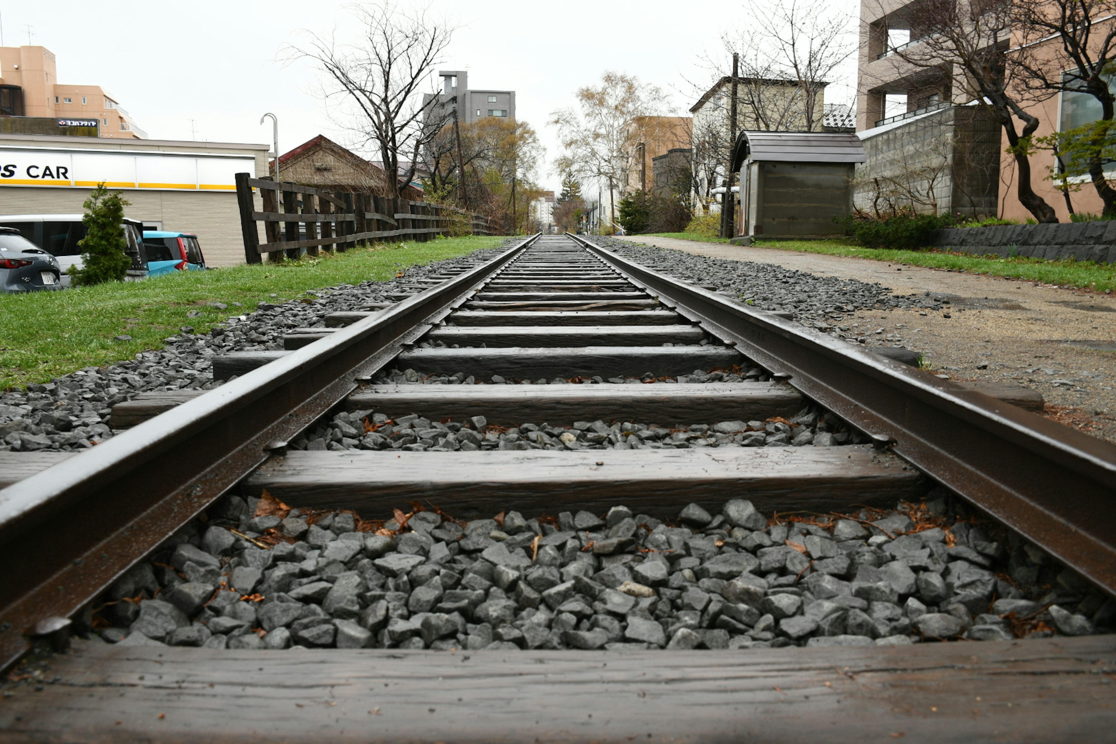 มุมมองต่ำของรางรถไฟพร้อมต้นไม้และอาคารรอบข้าง