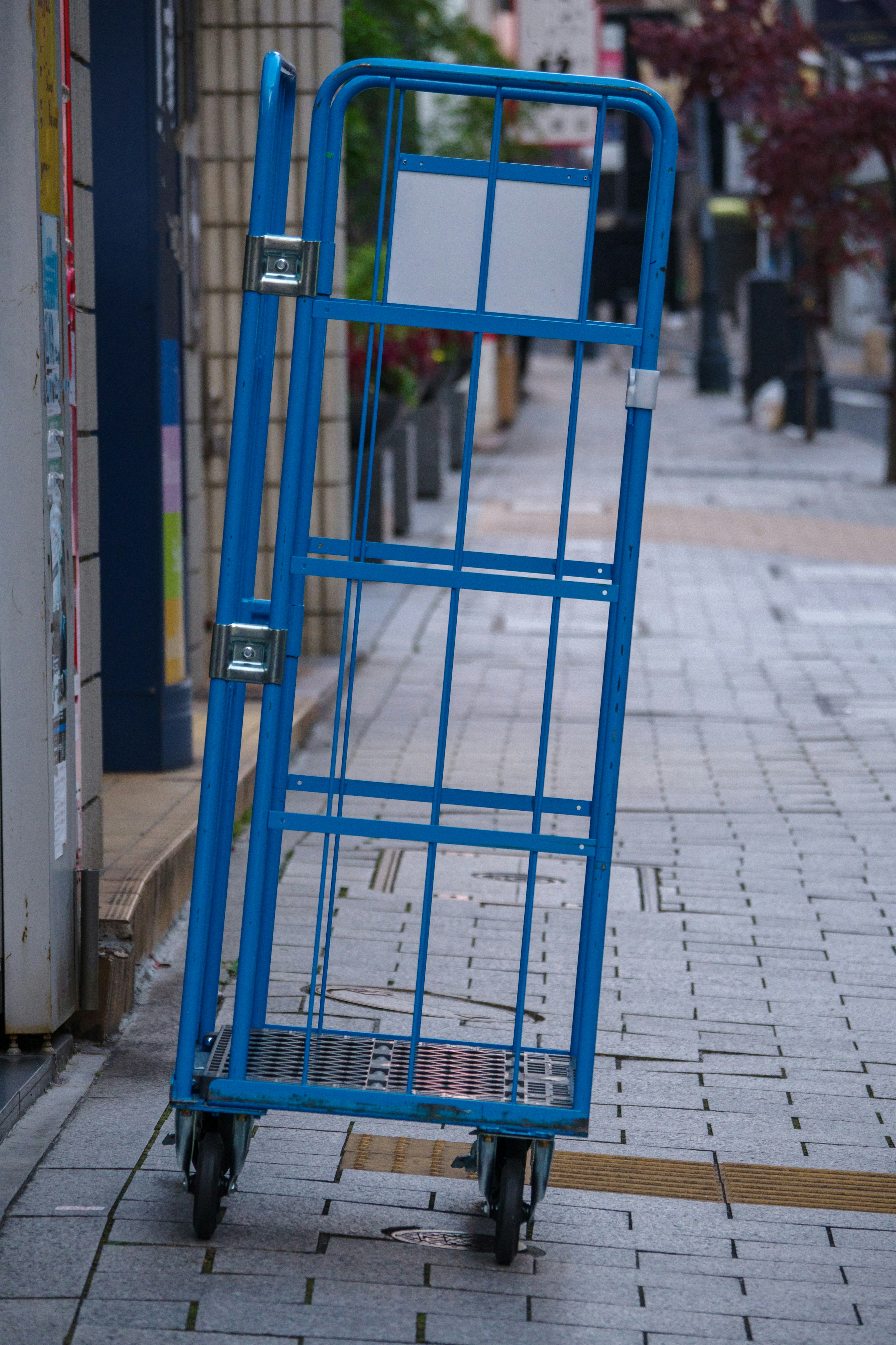 A blue transport cart leaning against the sidewalk