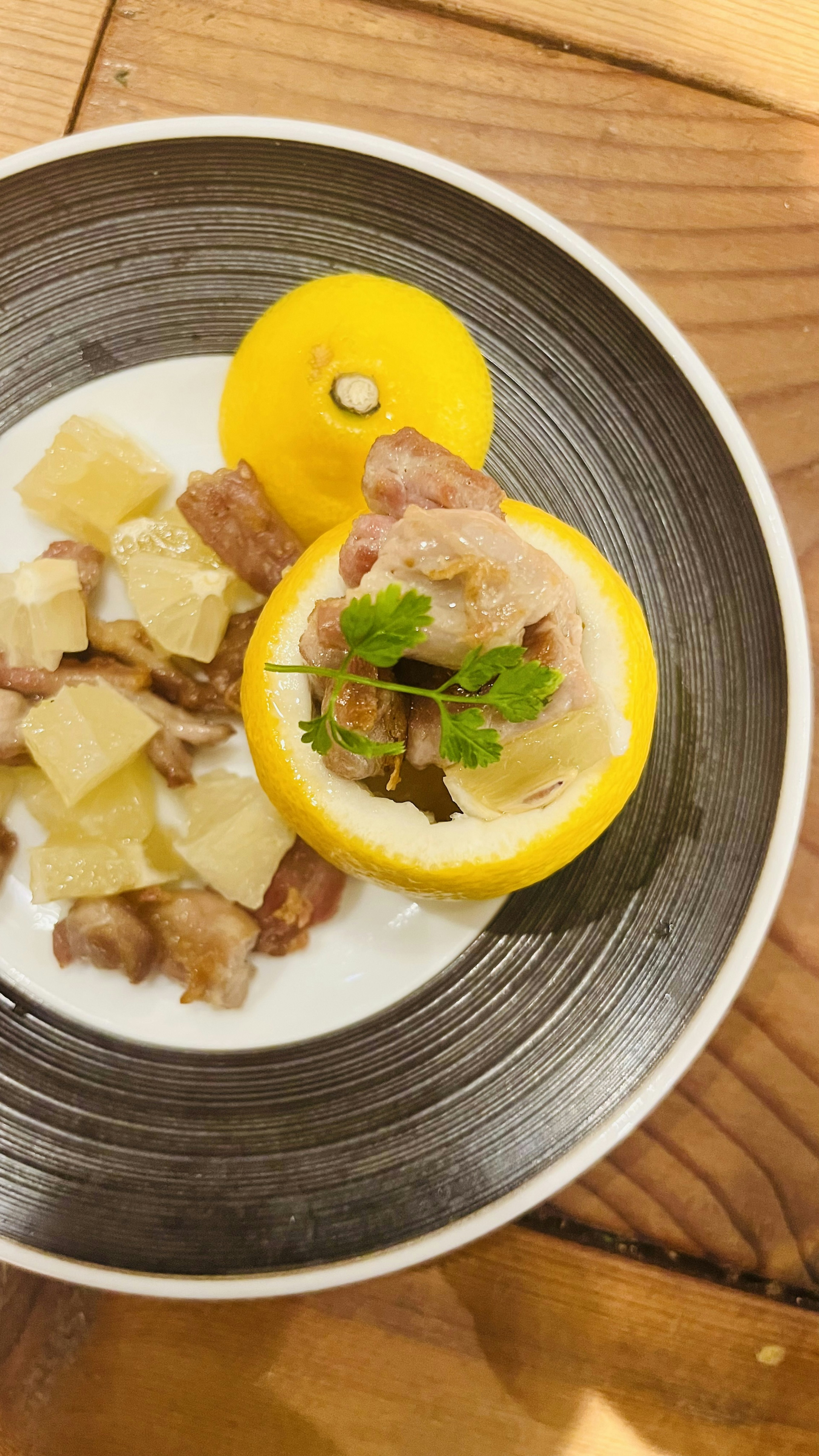 Dish served in a lemon with diced ingredients on a plate