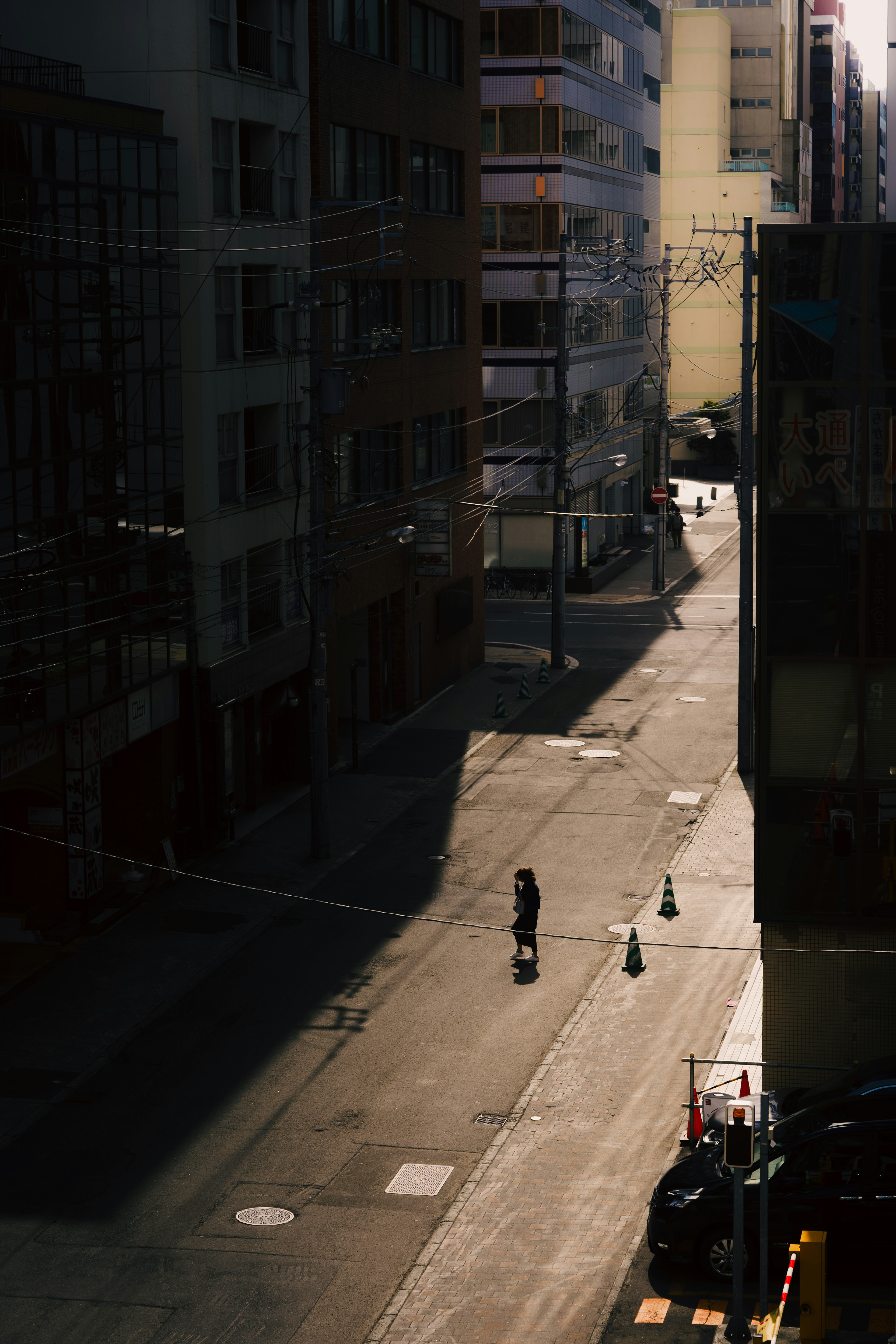 Eine Figur steht in einer schwach beleuchteten Straße mit kontrastierenden Schatten