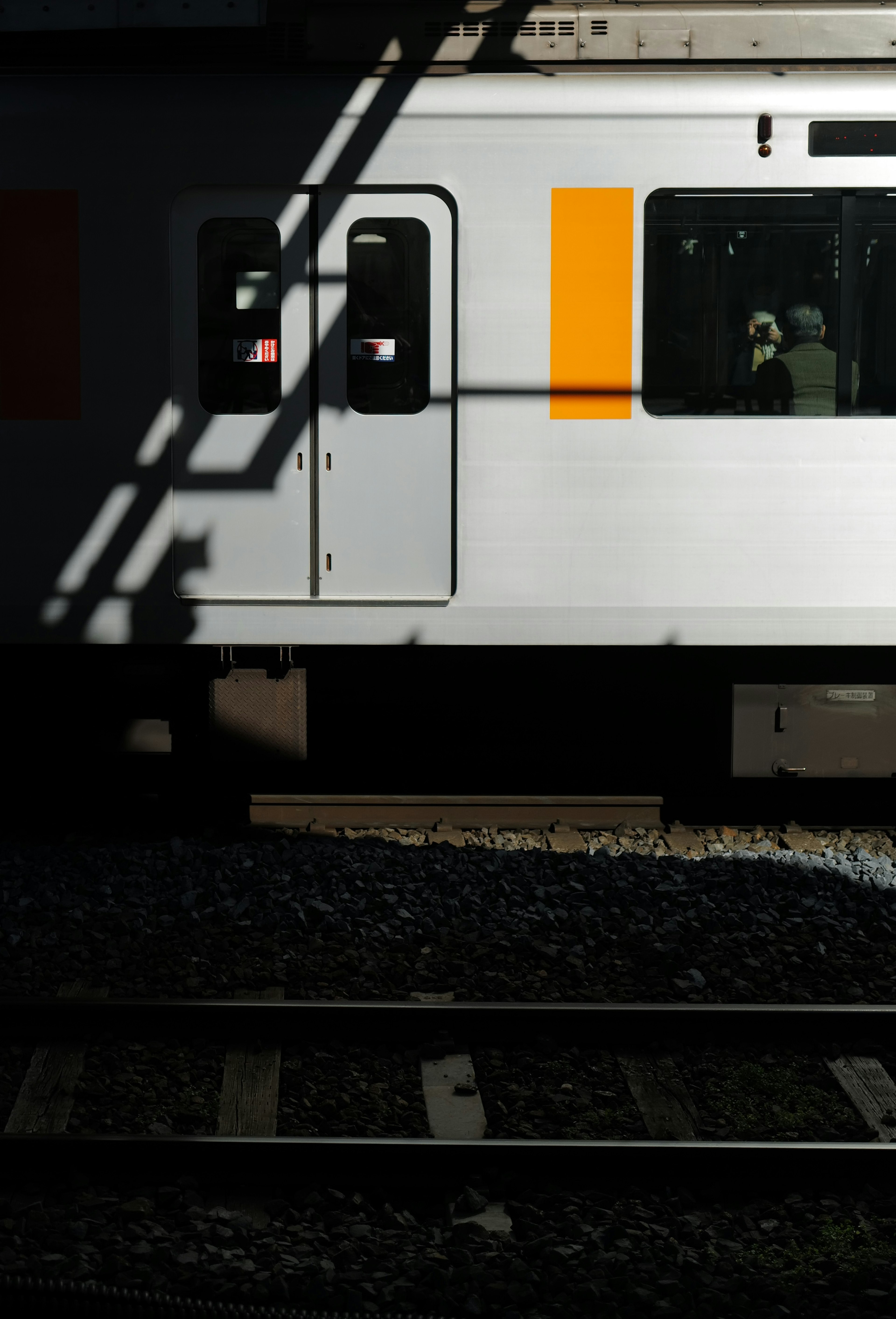 Side view of a white train with an orange accent in shadow